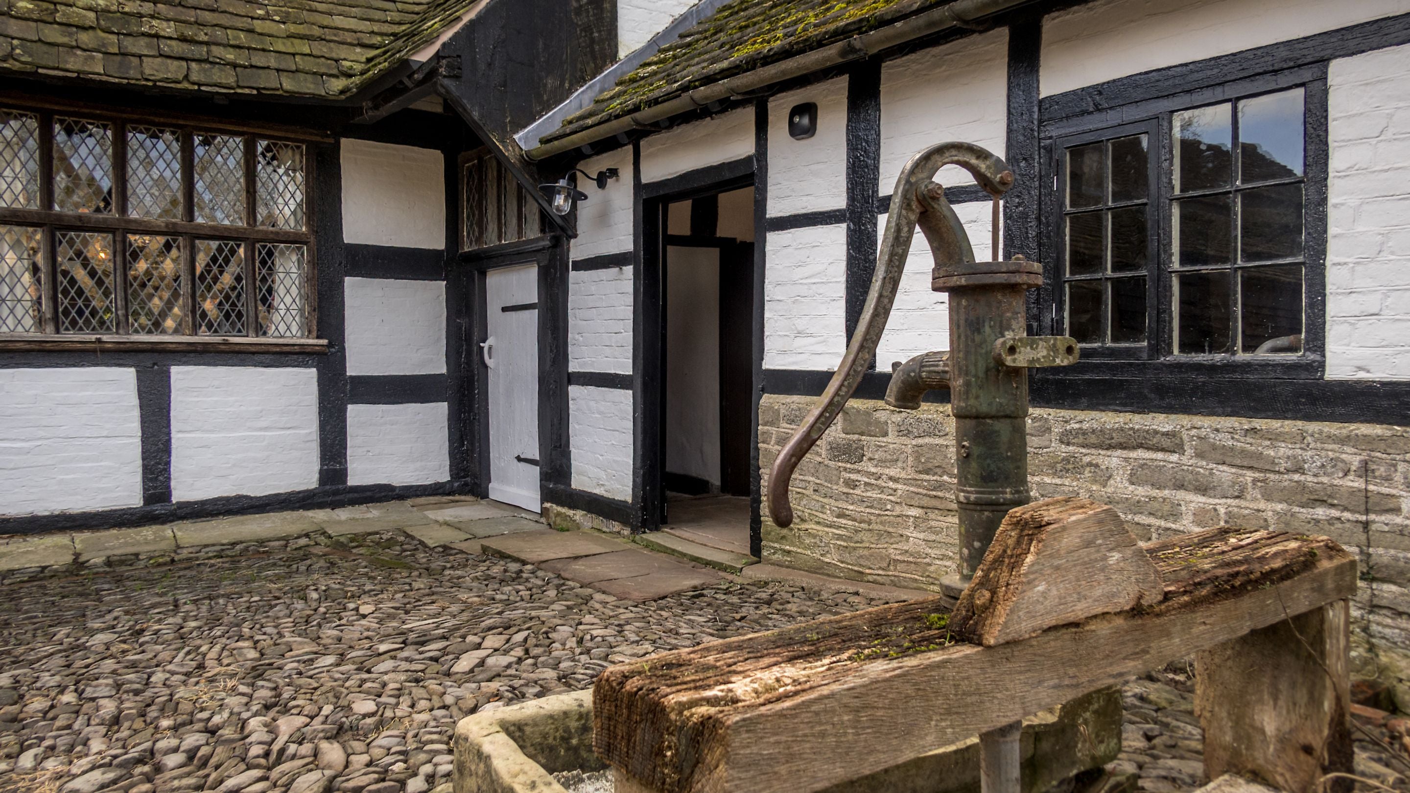 The cobbled courtyard with old water pump at Cwmmau Farmhouse, Herefordshire