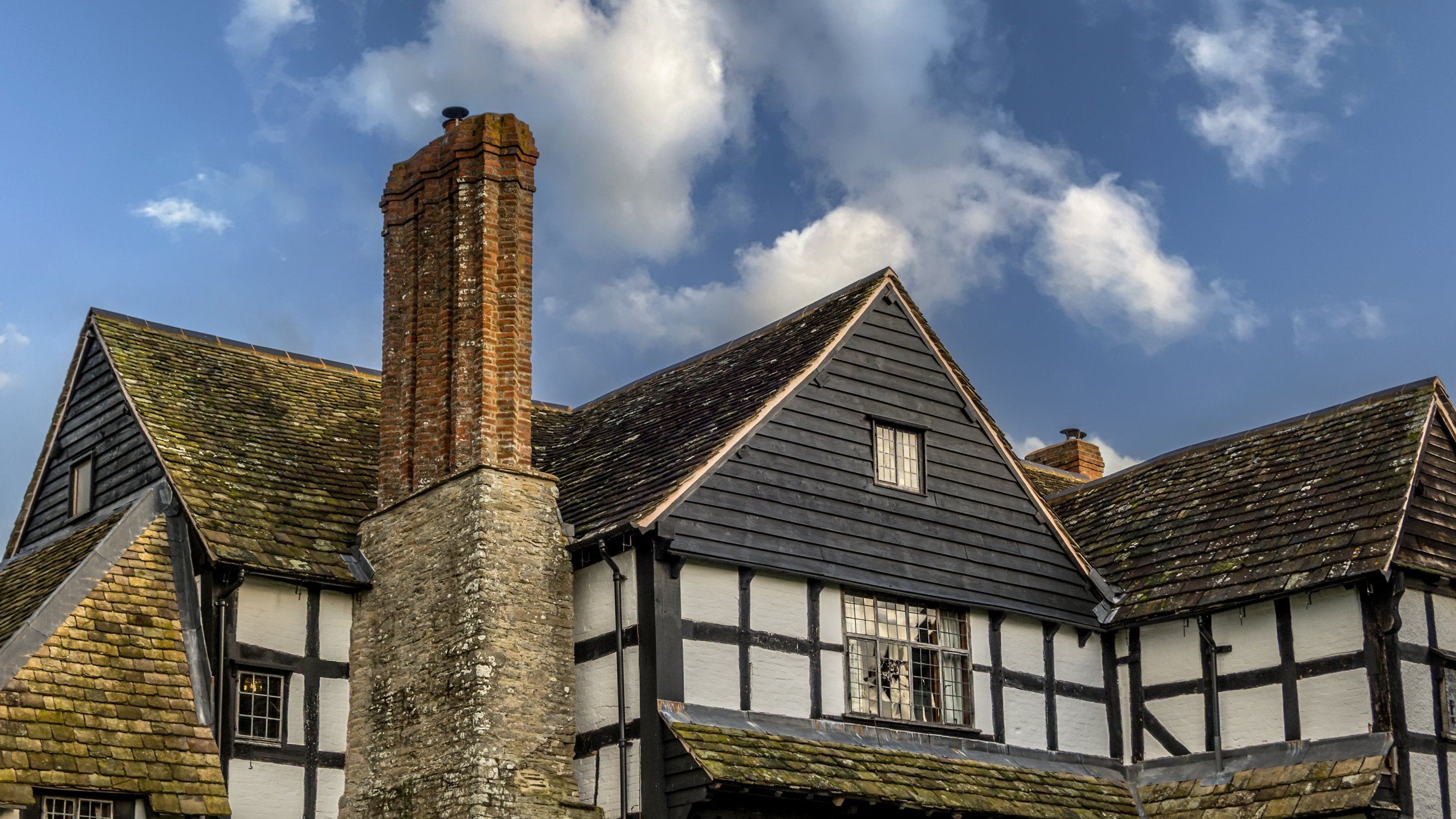 The exterior of the first floor of Cwmmau Farmhouse, with pitched roof and large chimney, Herefordshire
