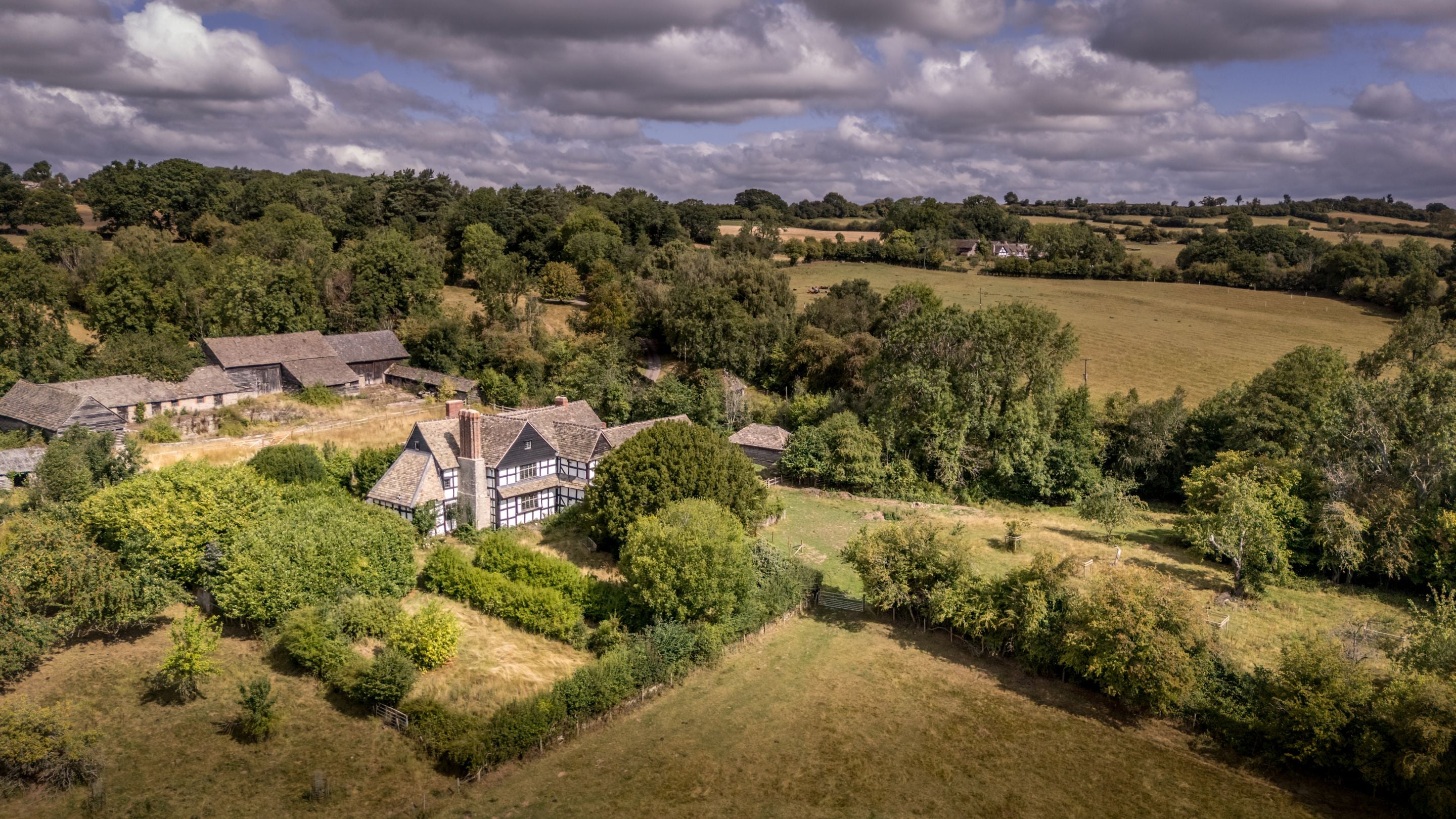 Cwmmau Farmhouse under restoration, showing the farmhouse and the surrounding buildings and landscape, Herefordshire