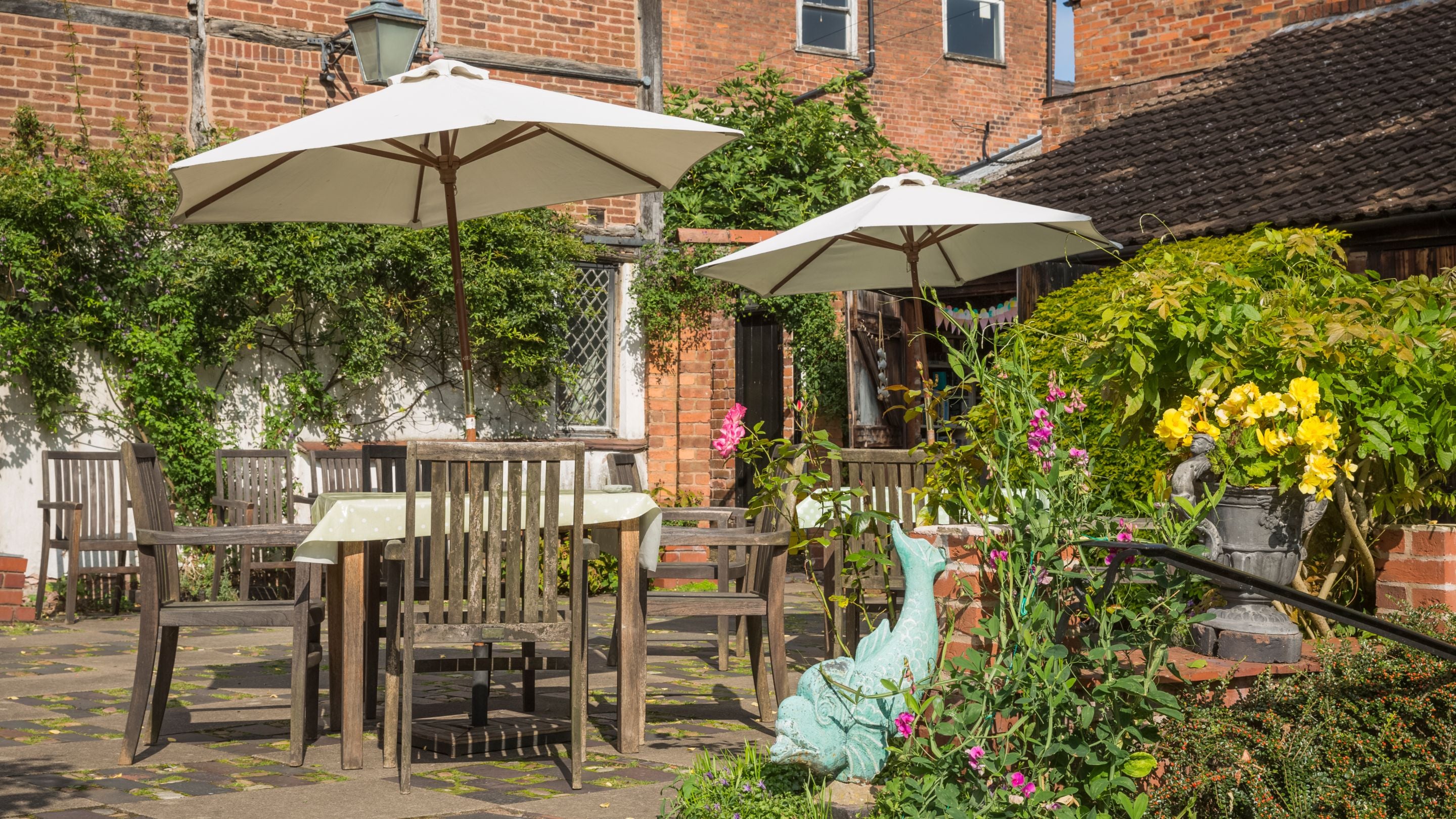 The café terrace in Greyfriars Garden with outdoor tables and chairs under parasols, Worcestershire