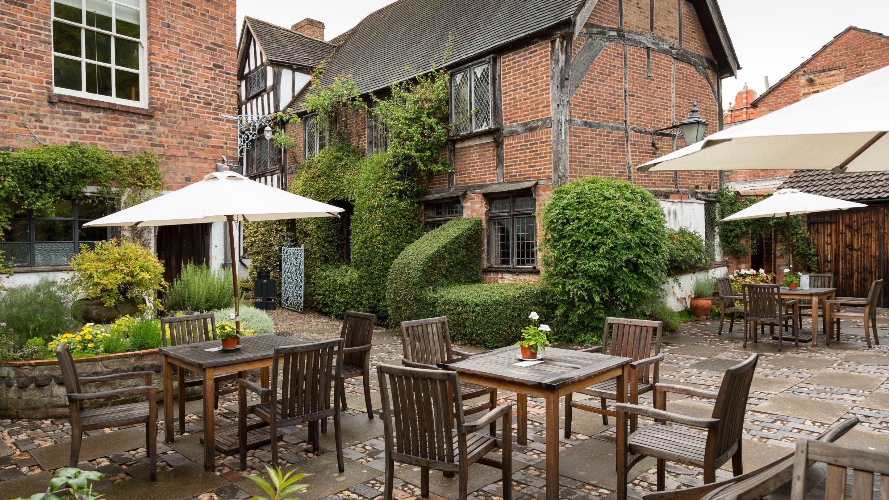 The café terrace in Greyfriars Garden, with tables and chairs under parasols, Worcestershire