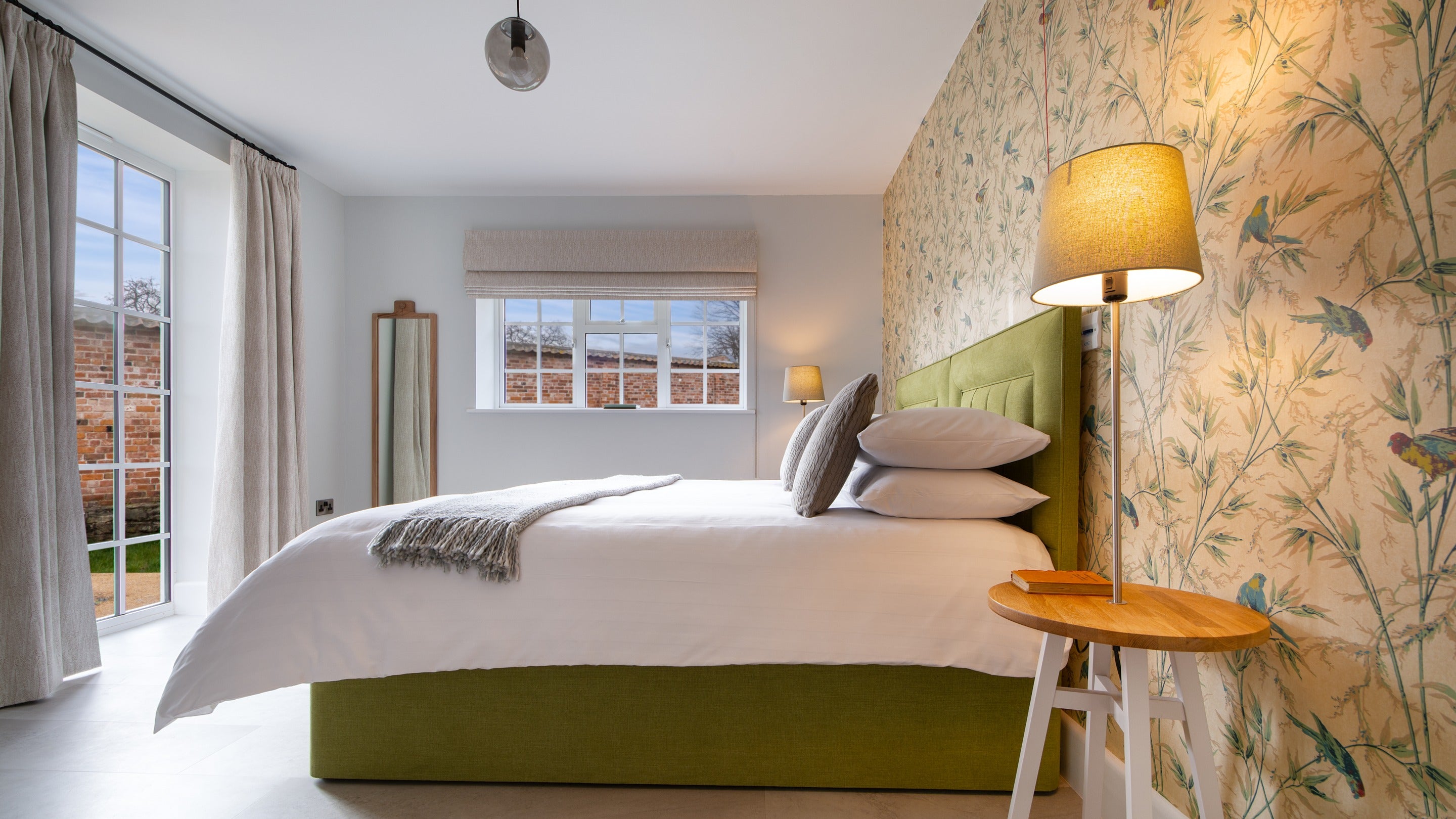The accessible double bedroom has full length windows that look onto the garden at The Weir Garden Cottage, Herefordshire