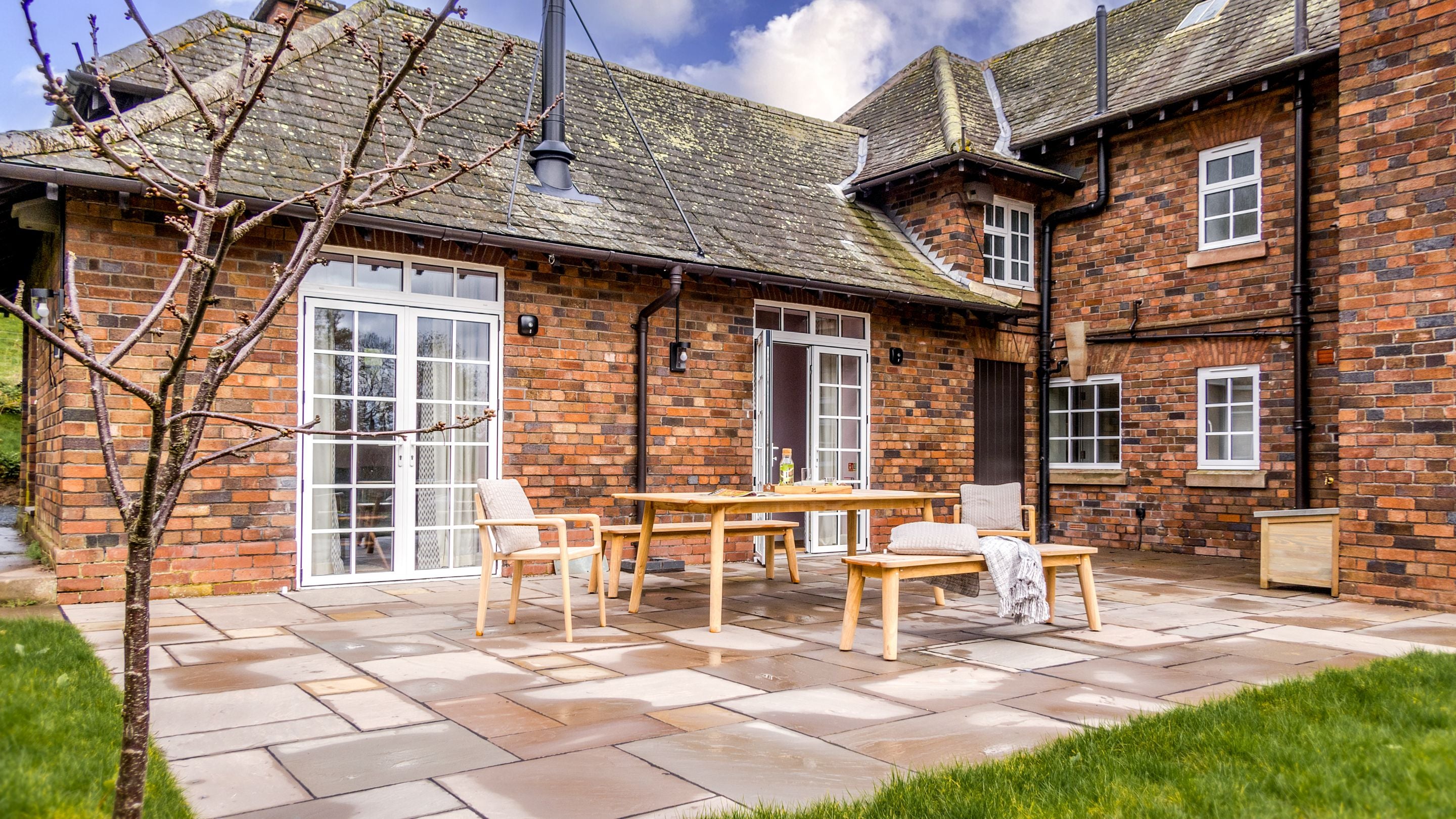 The patio with outdoor table and seating at The Weir Garden Cottage, Herefordshire