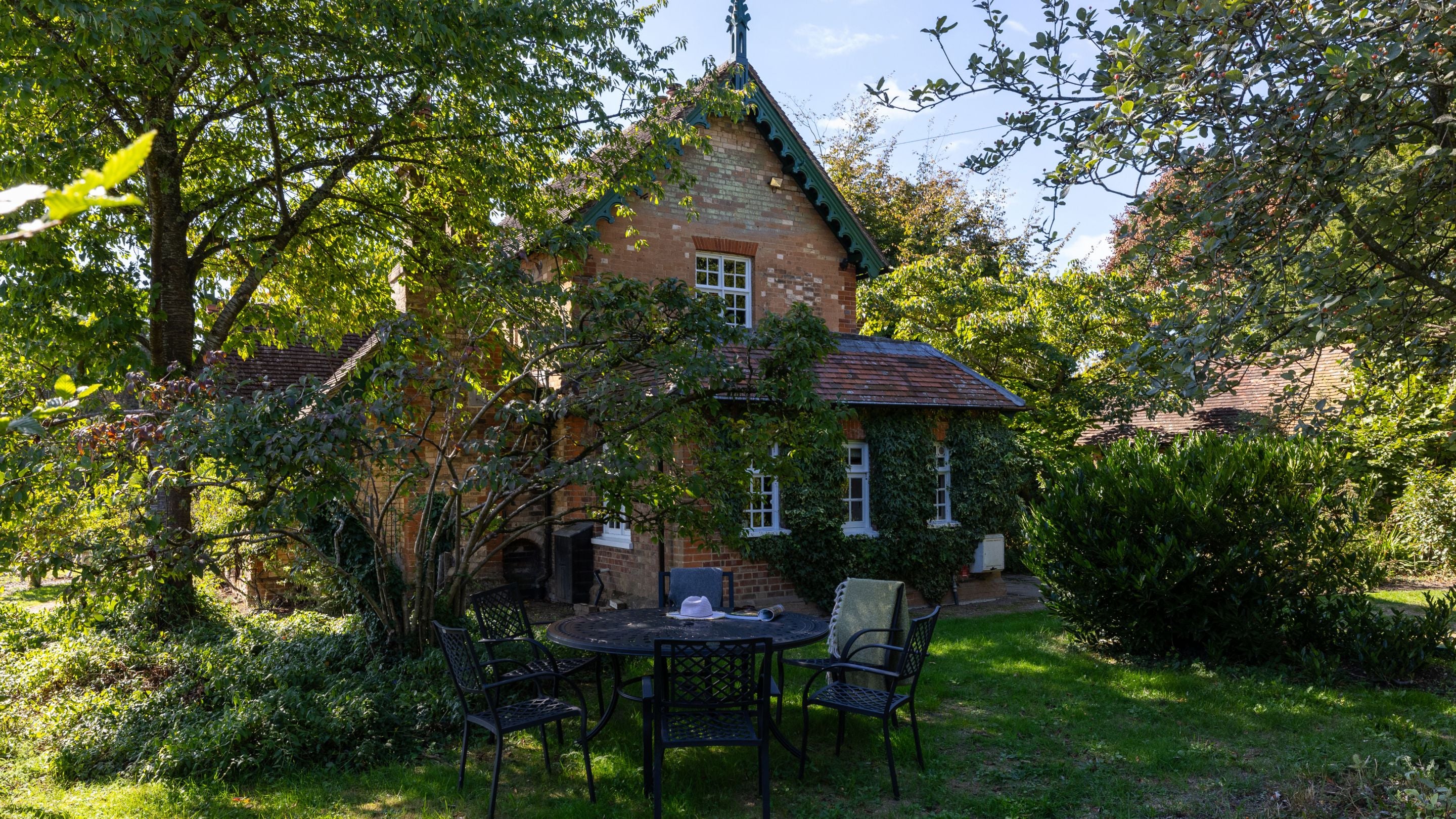 The private garden with patio, lawn and outdoor dining furniture at at Polesden Garden Cottage, Surrey
