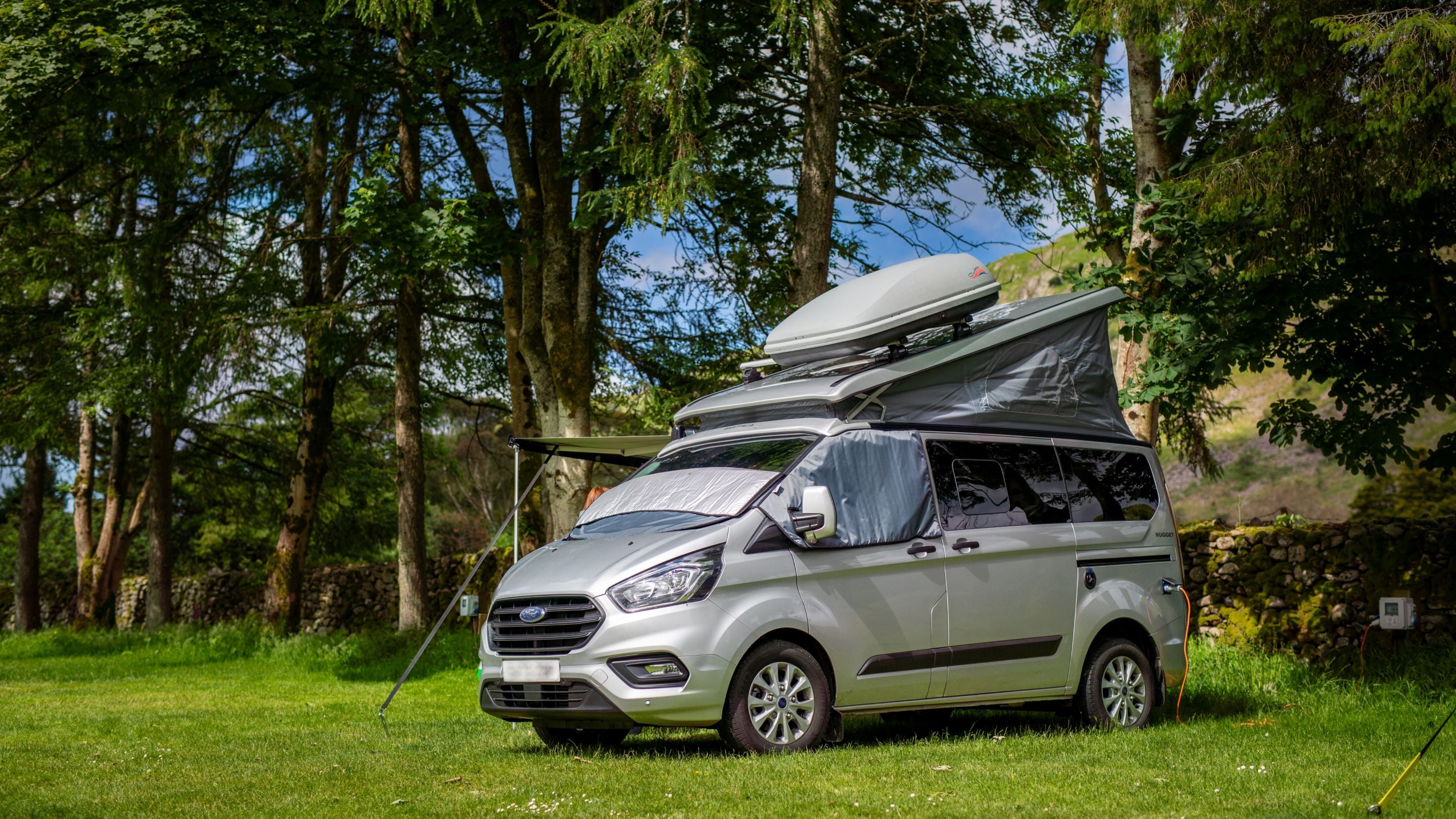 A campervan on a dual-use pitch with electrical hook-up at Eskdale Campsite, Cumbria