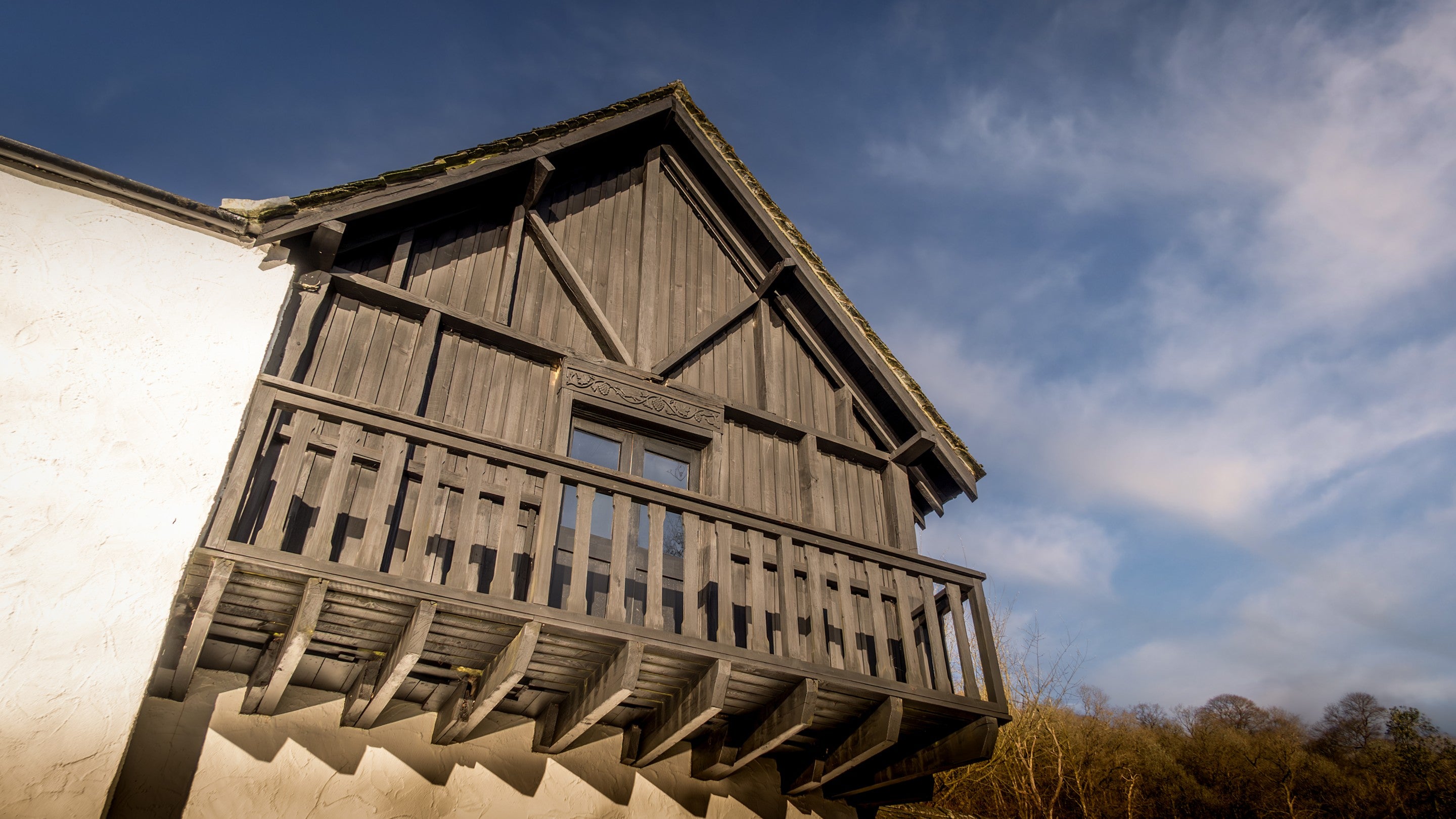 Looking up at the wooden exterior and balcony of the first floor of High Strawberry Gardens, Cumbria