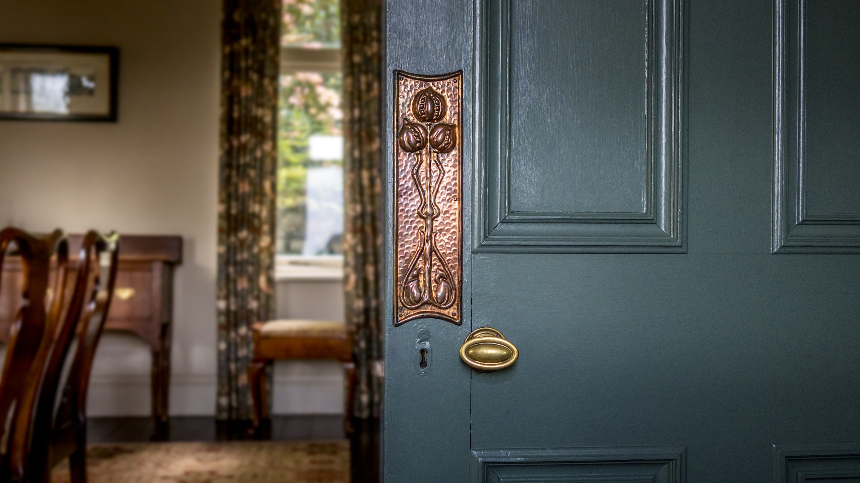 The dining room door with copper work from the Keswick School of Industrial Arts - an original piece from the conversion from the mill to a house - at Millbeck Towers, Cumbria