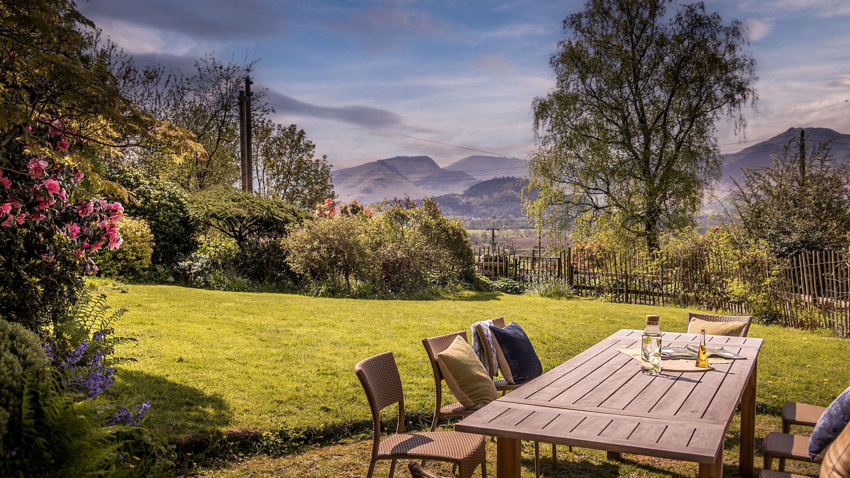 The front garden at Millbeck Towers with outdoor dining area and expansive views towards the fells around Derwentwater, Cumbria