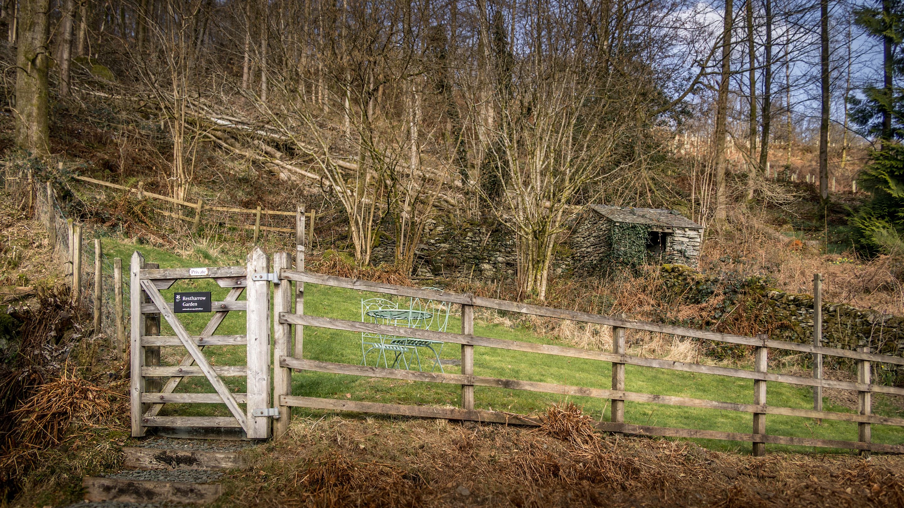 The private garden at Restharrow, with a sloped lawn and garden furniture, Cumbria