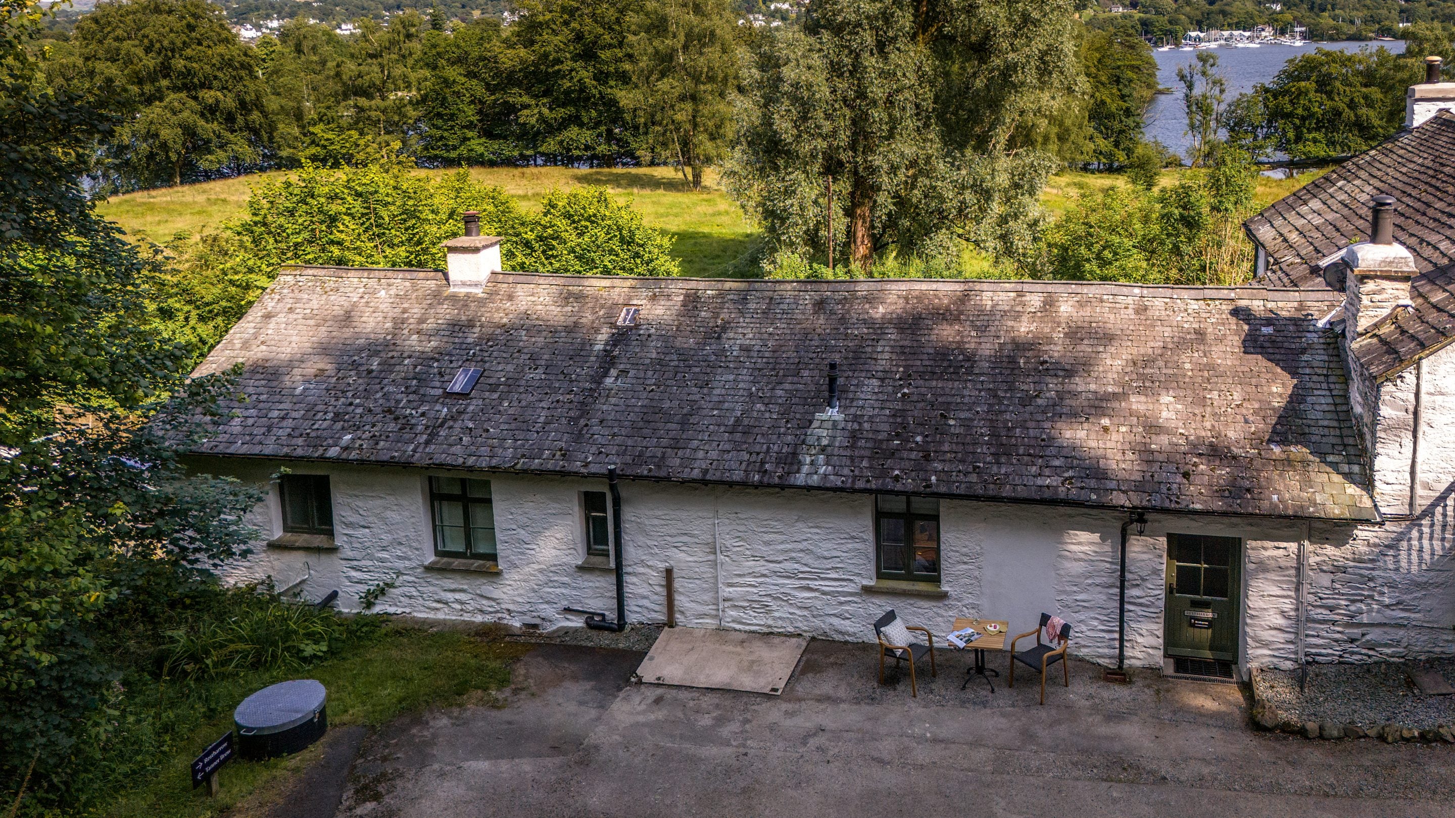 The exterior of Restharrow (door and one window on the right) and one of its neighbours (three windows on the left) with Lake Windermere one field away, Cumbria