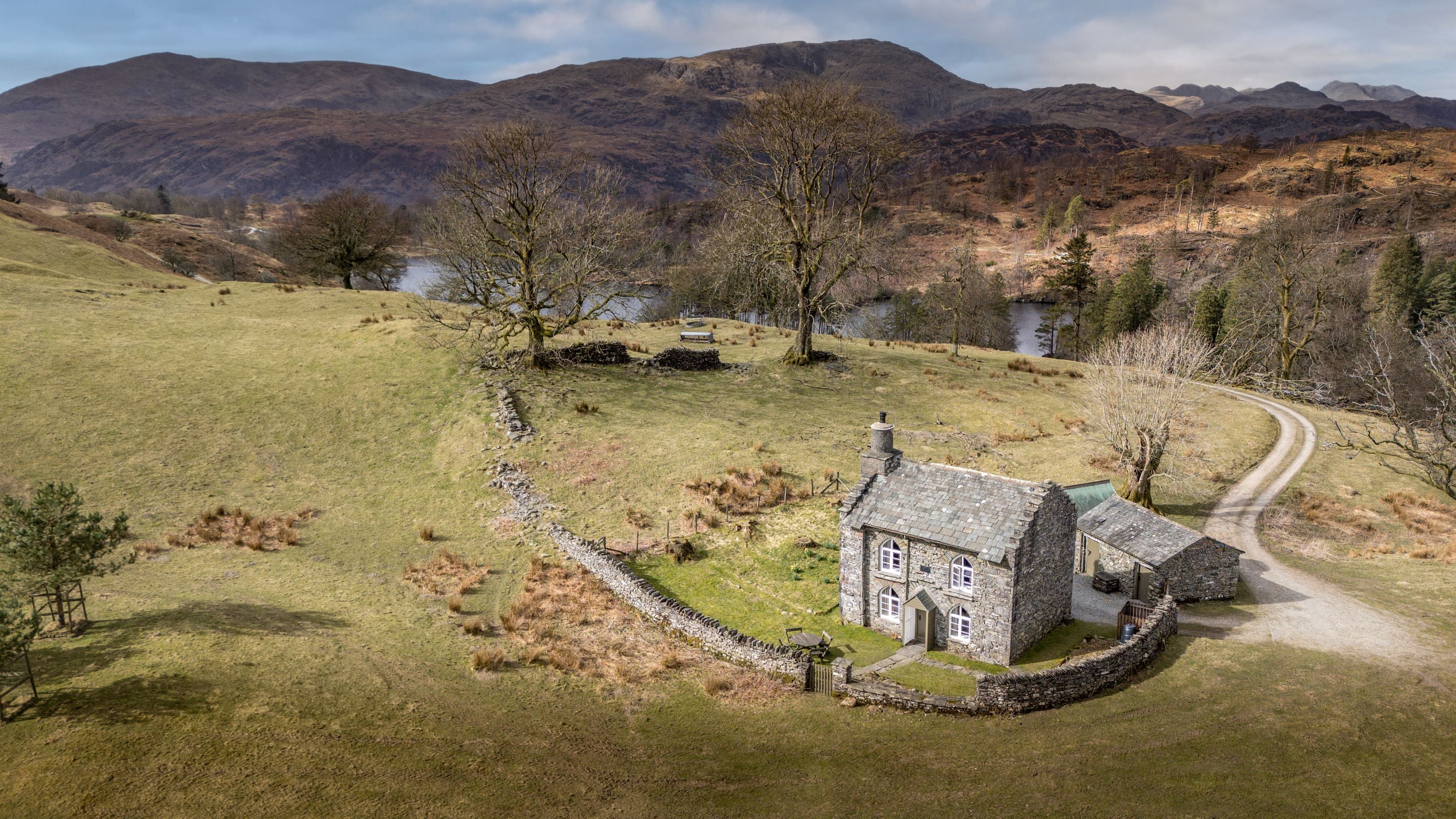 An aerial view of Rose Castle Cottage with the waters of Tarn How in the background, Cumbria