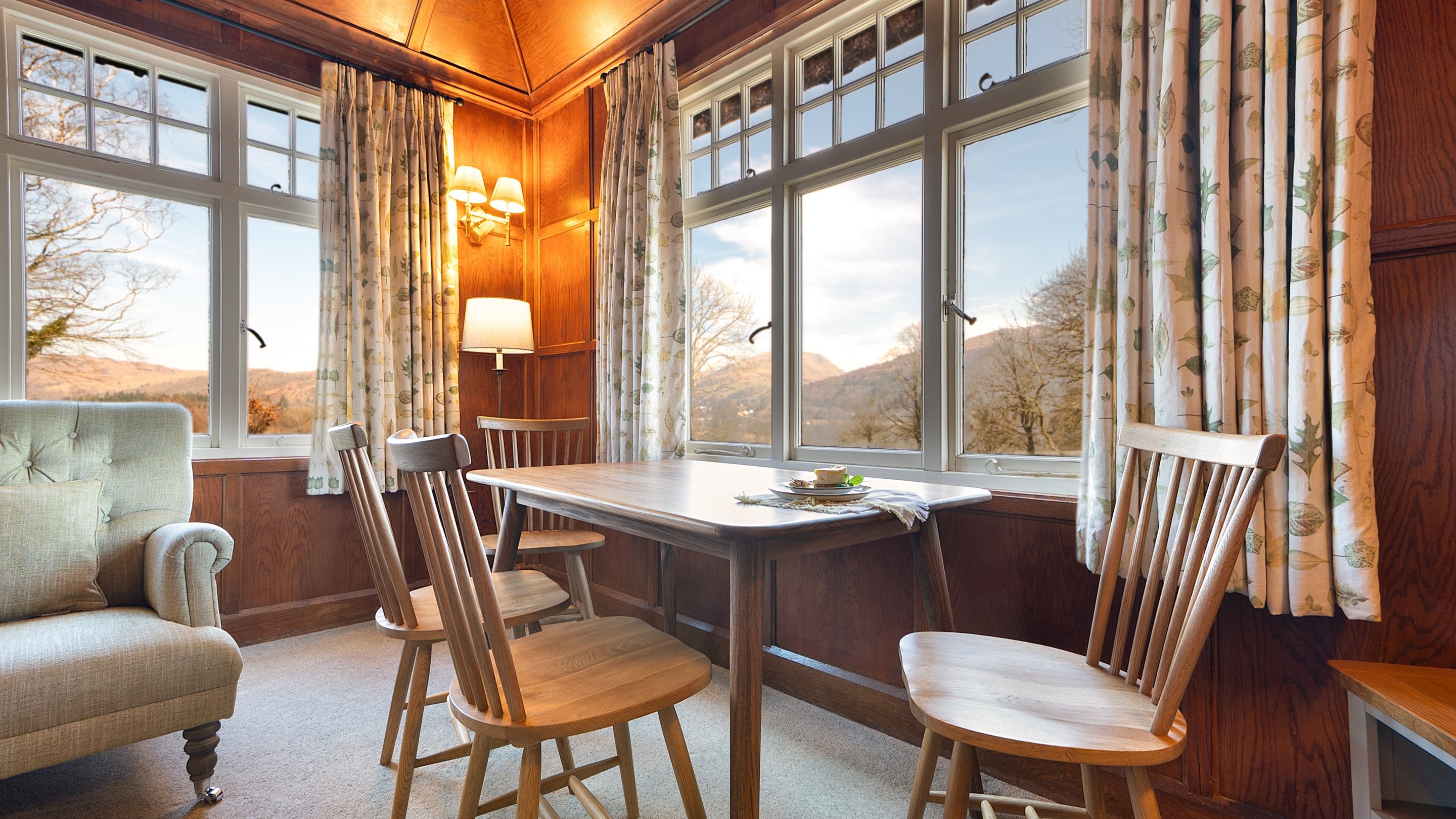 The dining table in the sitting room at The Summer House, with views towards Lake Windermere and of the surrounding hills from two windows, Cumbria