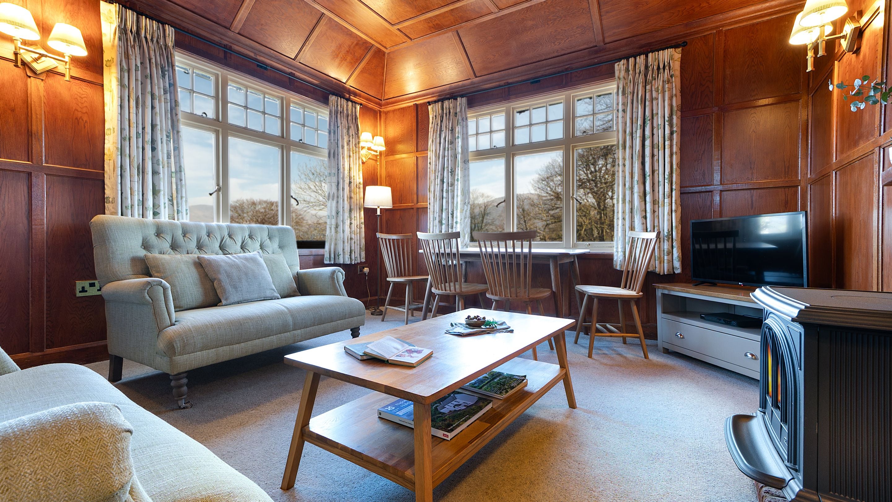 The sitting room at The Summer House, with two large windows with Lake District views, sofas, dining table and a television, Cumbria