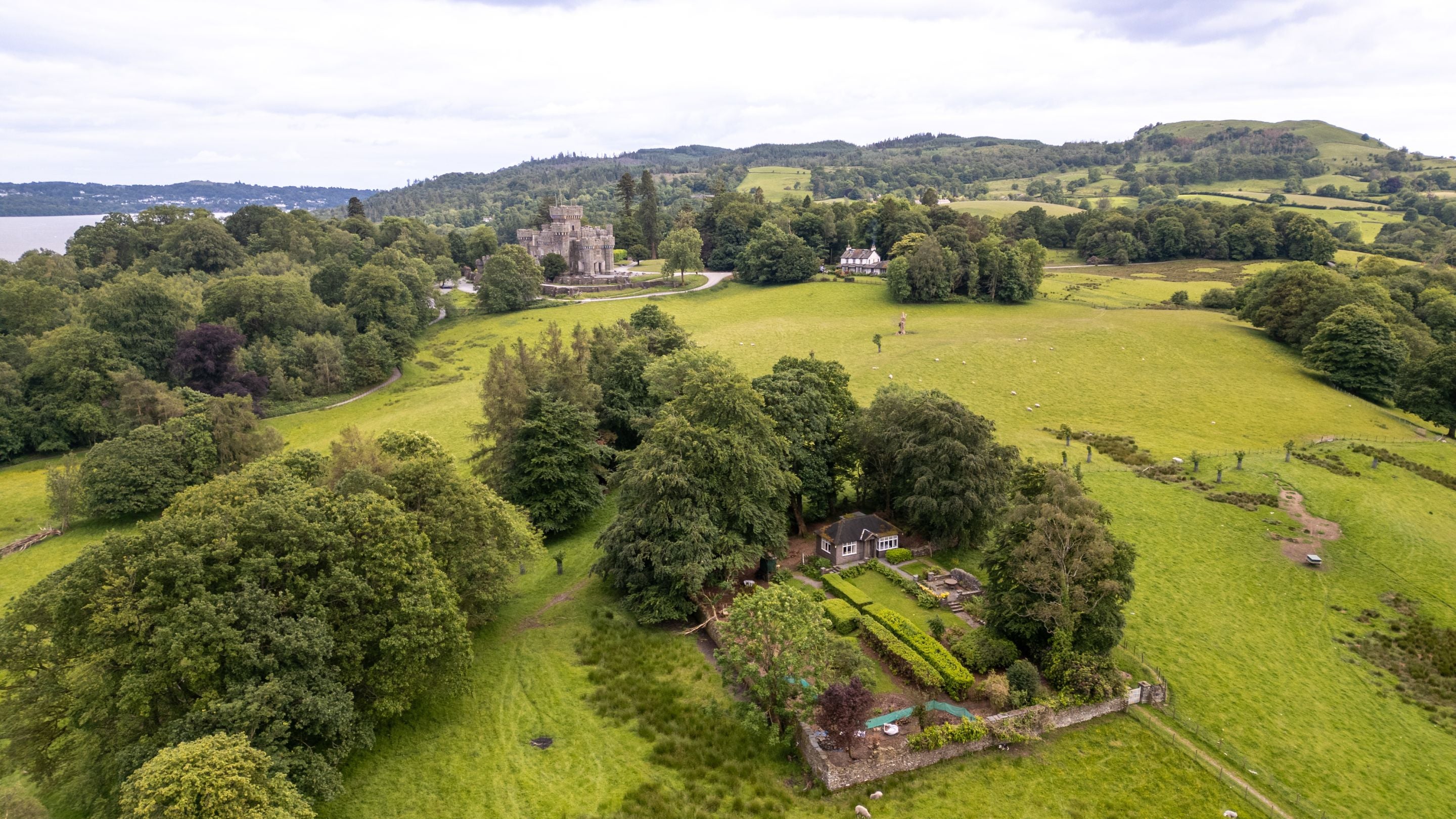 An aerial view of The Summer House with Wray Castle and Wray Castle House in the distance, Cumbria