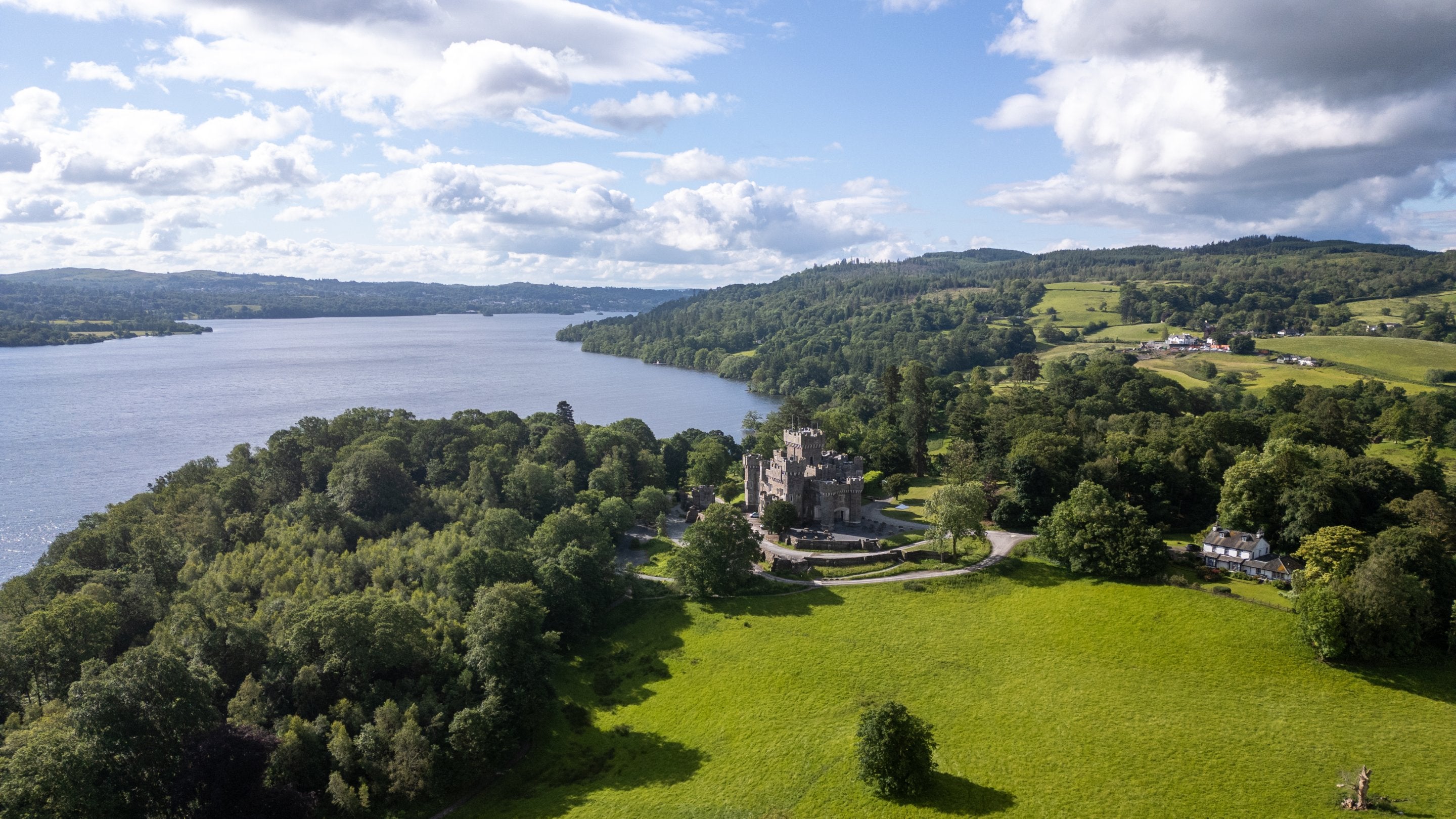 An aerial view of Wray Castle, with Wray Castle House on the right and Lake Windermere on the left, Cumbria