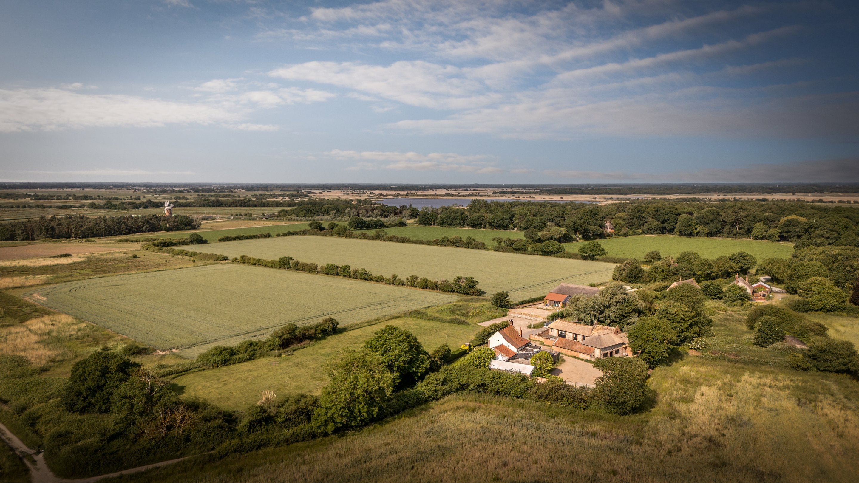 An aerial view of 1, 2 and 3 Horsey Barns, with Horsey Windpump and Heigham Holmes Nature Reserve in the distance, Norfolk