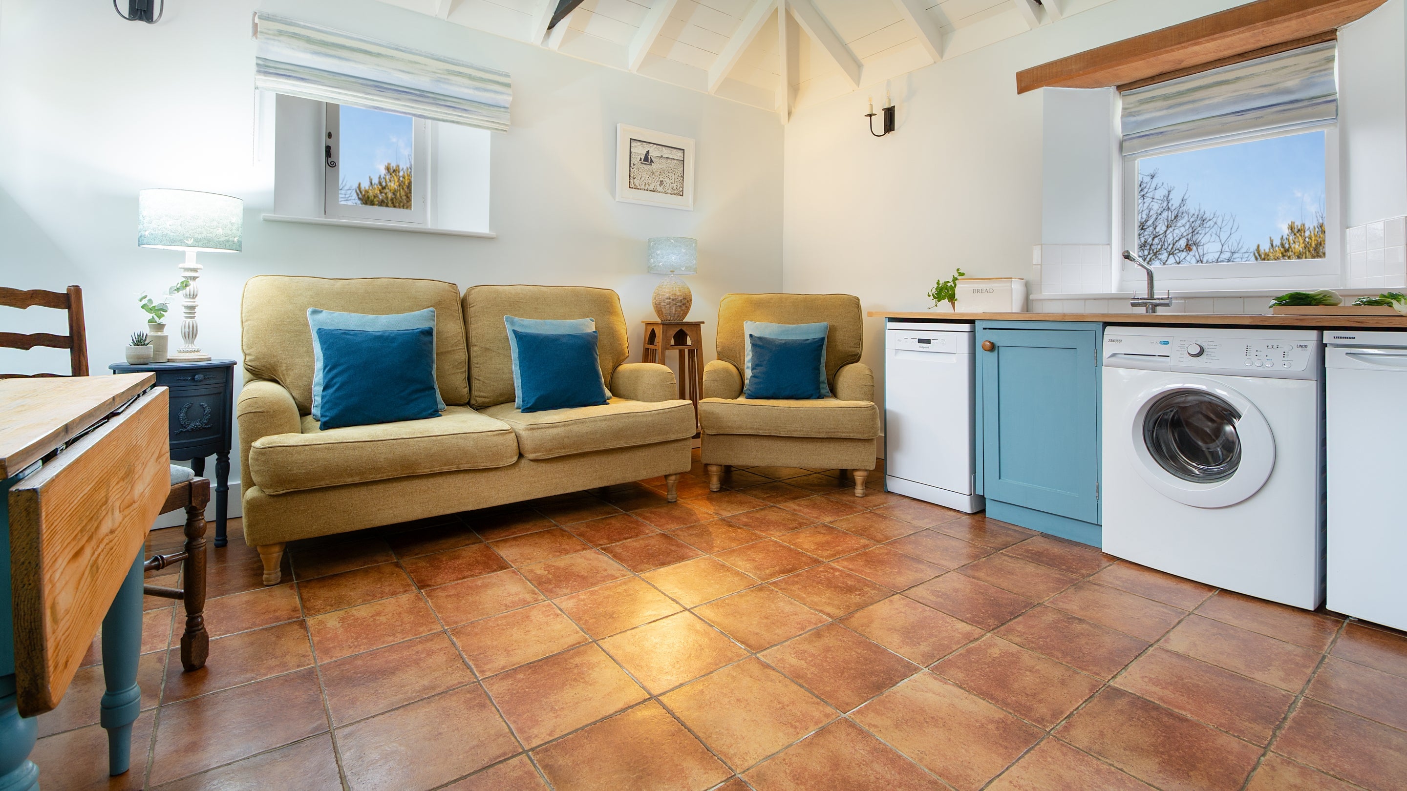 The open-plan living space at Blakeney Lodge with a kitchen, sofa and armchair, television and a dining table and chairs, Norfolk