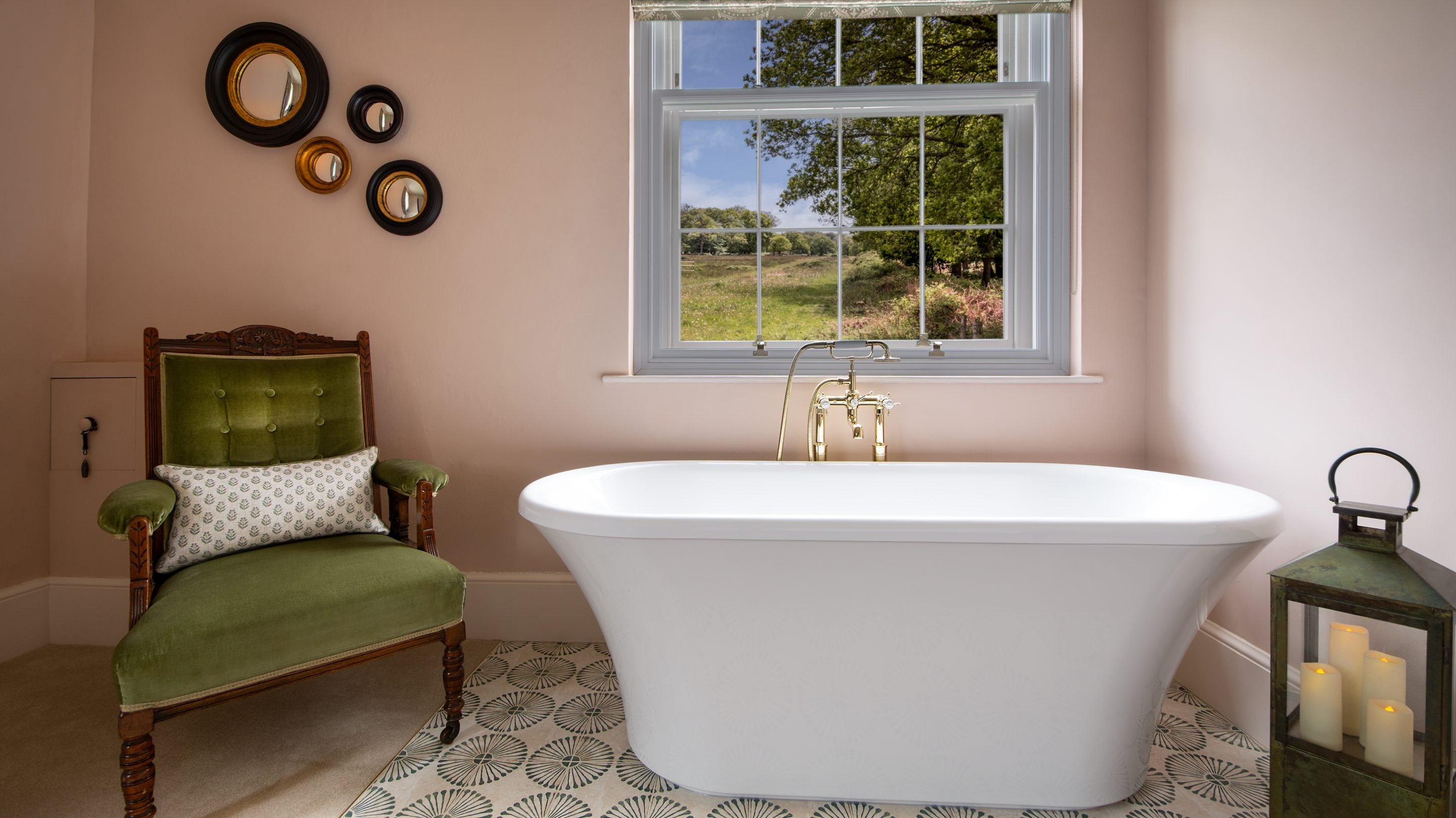 The freestanding bath under the window with a green velvet chair next to it, in the second-floor main bedroom at Blckling Tower in Norfolk