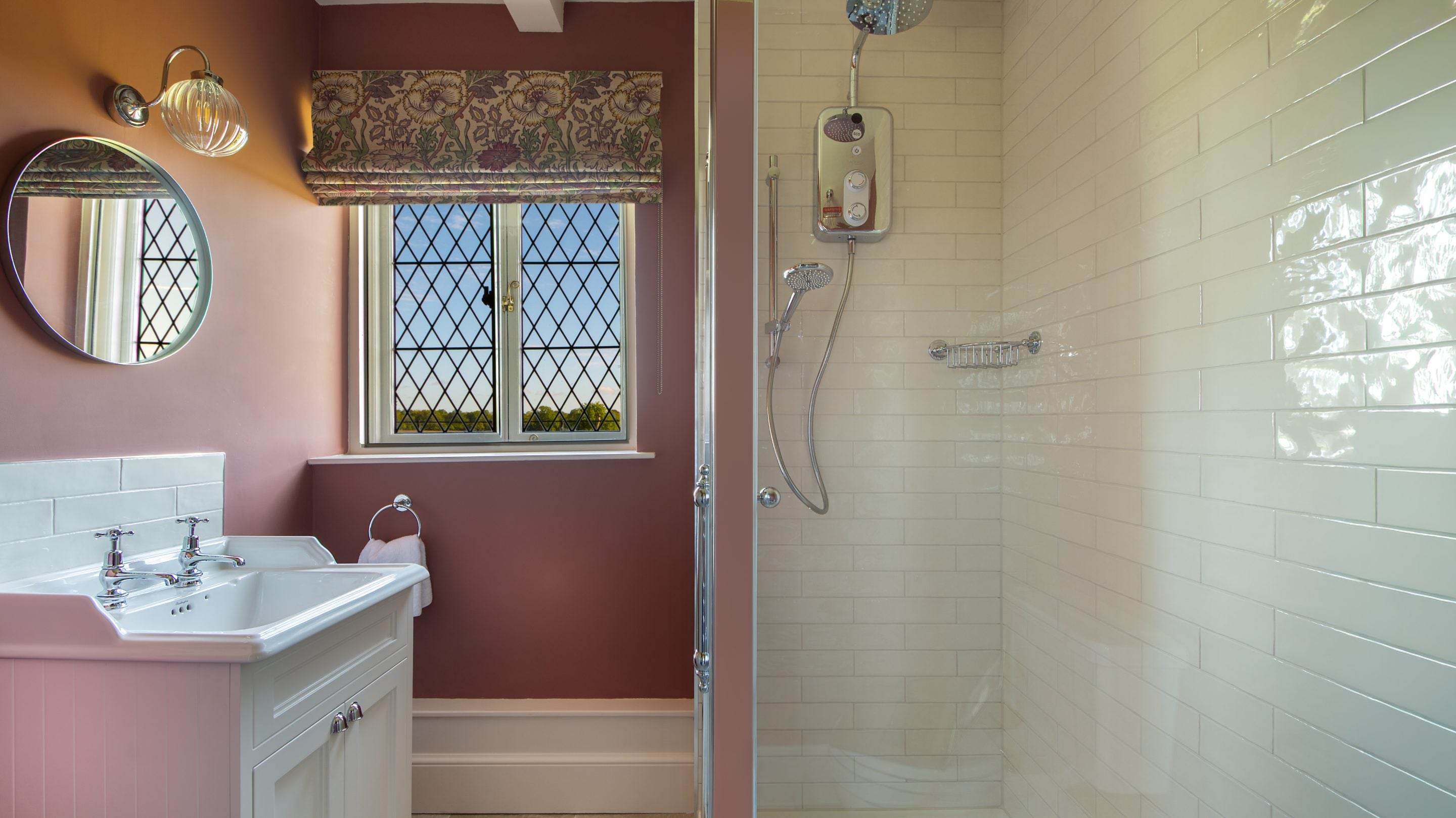 The ground-floor shower room at Blickling Tower, with a latticed window, dusky pink walls, white tiles and a freestanding shower, Norfolk
