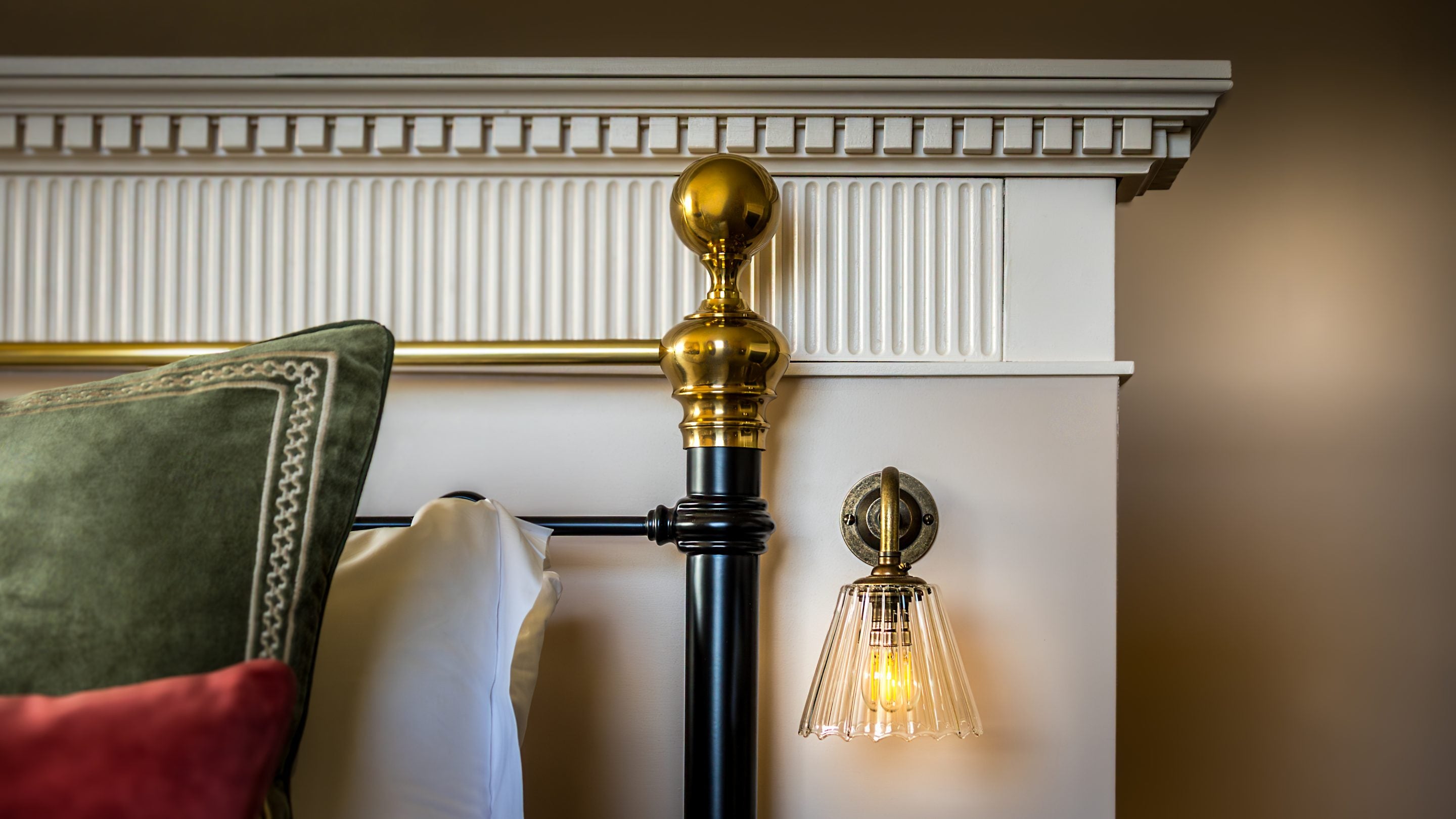 A close-up view of the black and gold metal bedroom and glass wall lamp in the main bedroom on the second floor at Blickling Tower, Norfolk