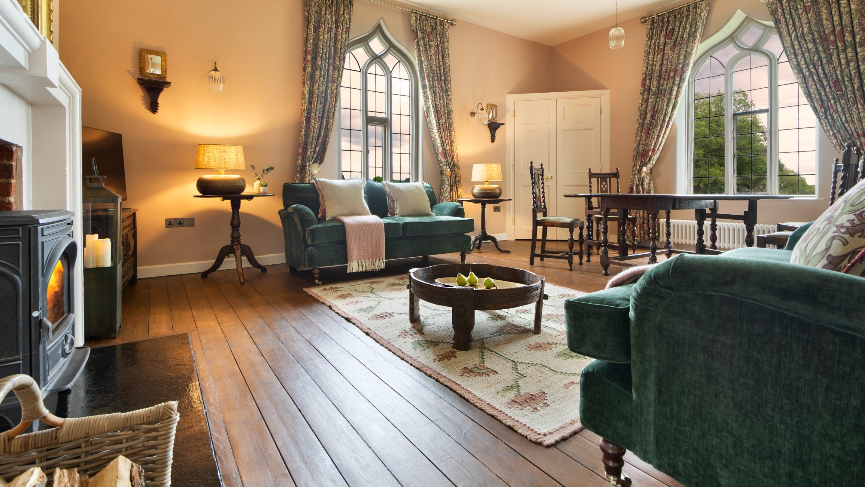 The sitting room at Blickling Tower with two large windows, a woodburner, two sofas and a dining table with two chairs