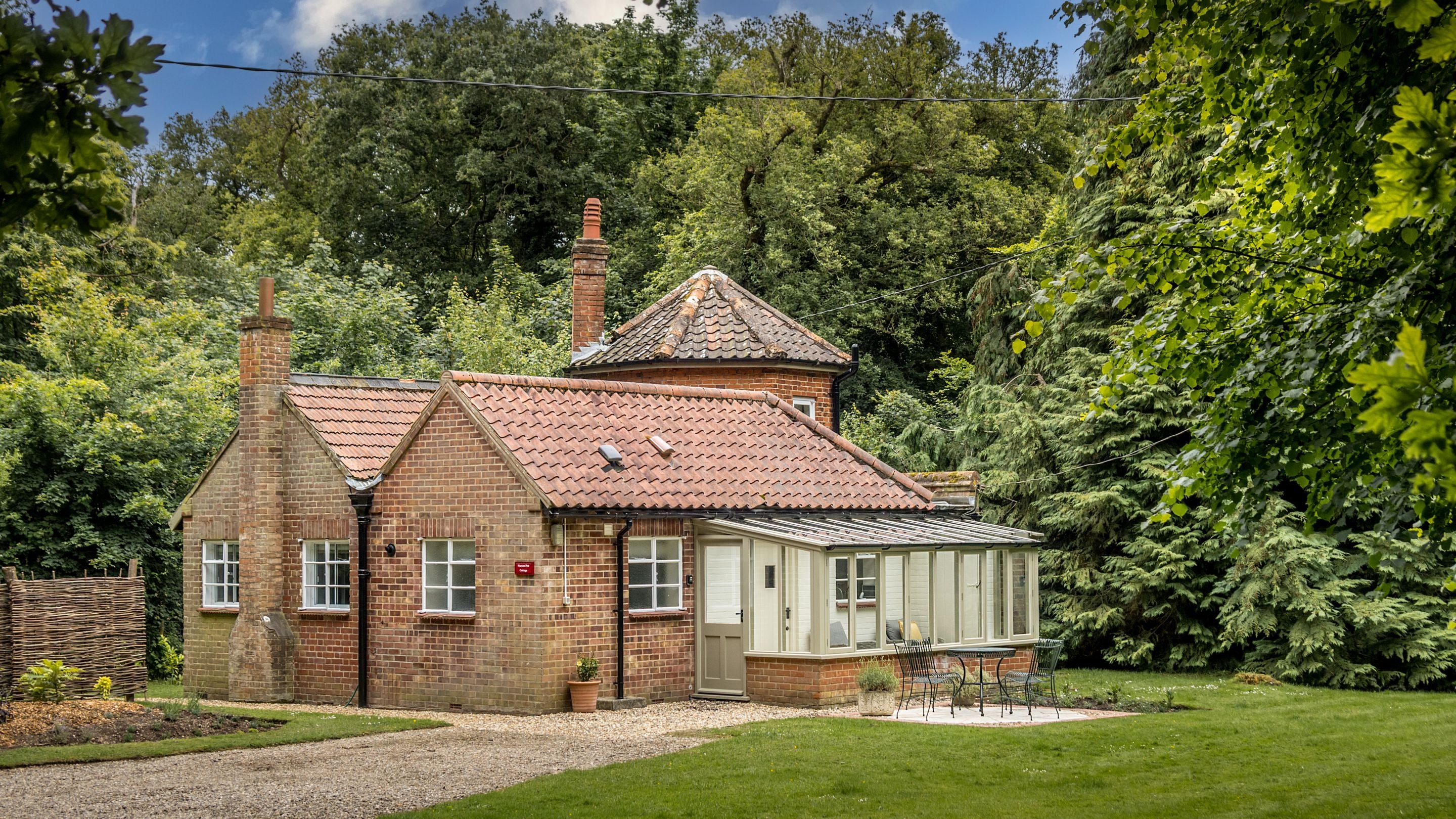 The exterior and garden of Mustard Pot Cottage, surrounded by trees, Norfolk