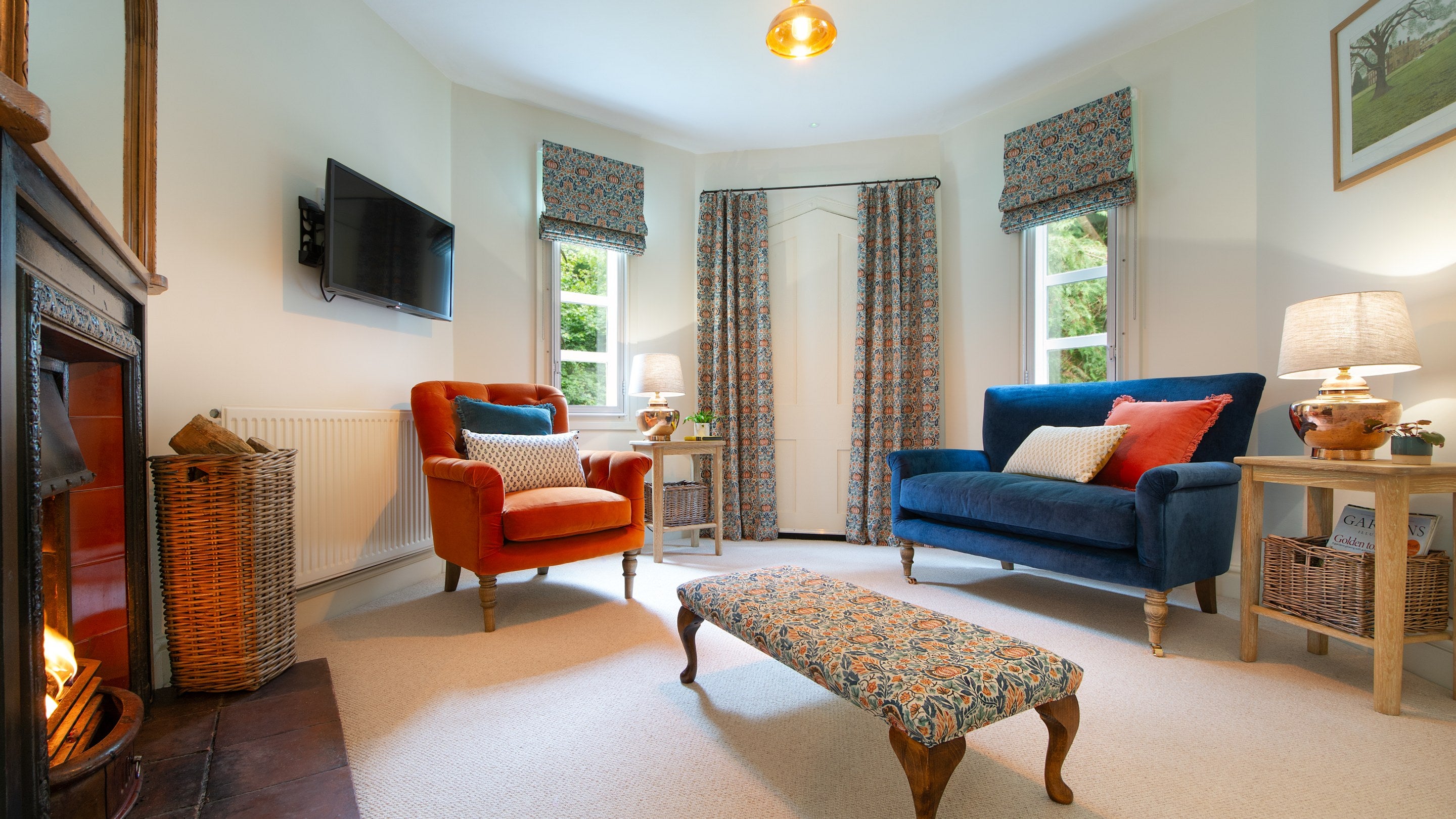 The sitting room with sofa, armchair, television and open fire at Mustard Pot Cottage, Norfolk