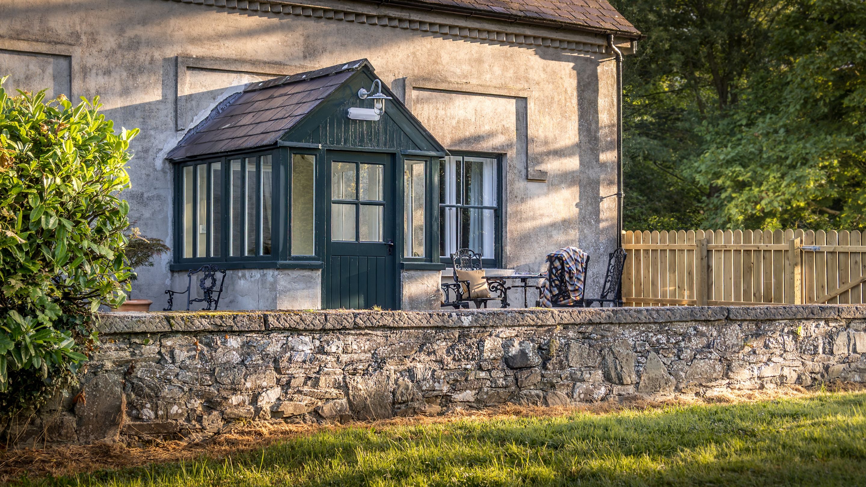 Part of the garden at Castle Ward Gamekeeper's Lodge, with outdoor seating on the gravelled area and lawn beyond, County Down