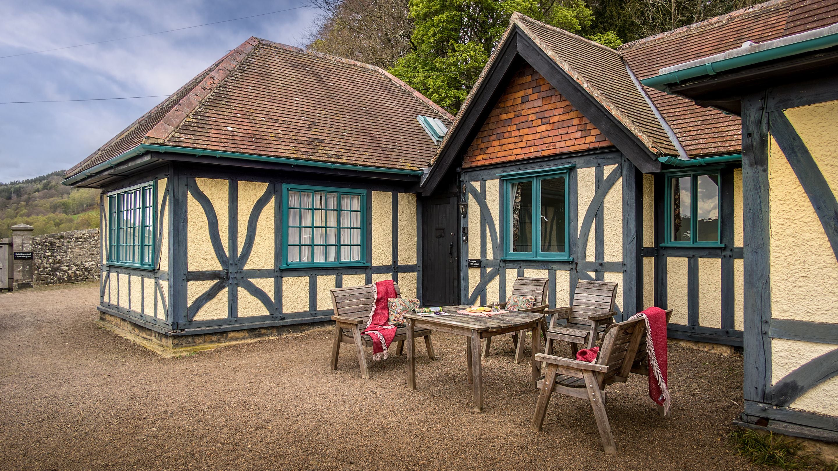 The gravelled garden at the front of Cragside Park Cottage, with outdoor dining furniture, Northumberland