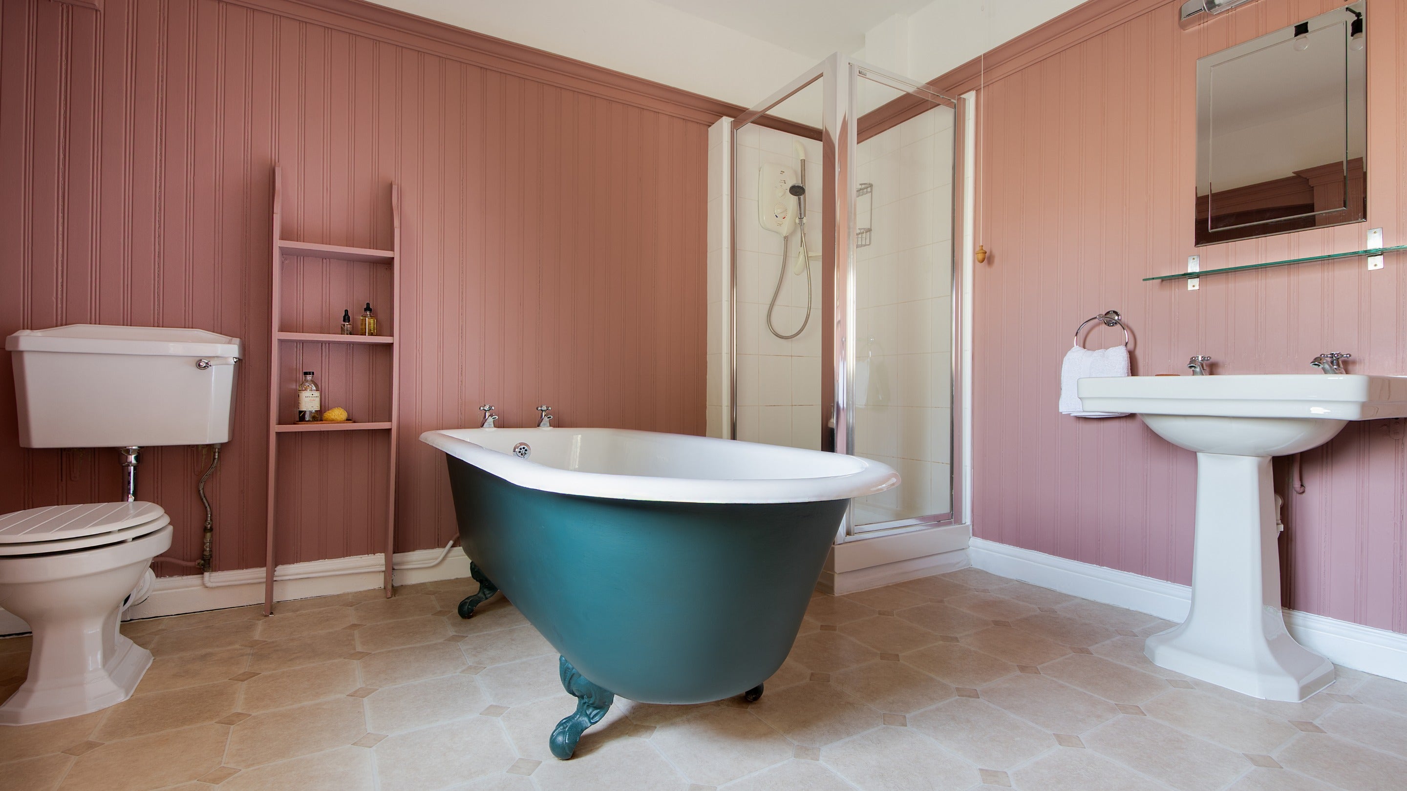 The ground-floor bathroom at Cragside Park Cottage, with cast iron roll-top bath and freestanding shower, Northumberland