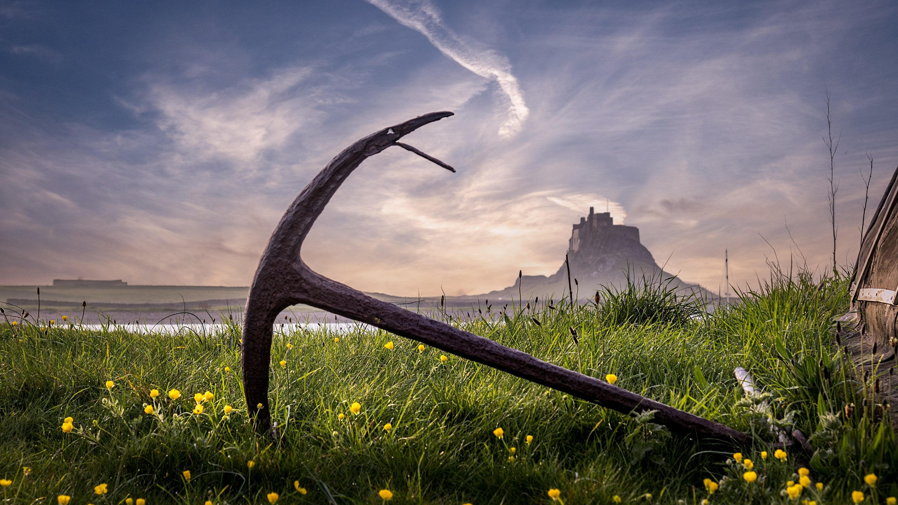 An anchor next to a boat shed on Holy Island, with Lindisfarne Castle in the background, near Glen House, Northumberland