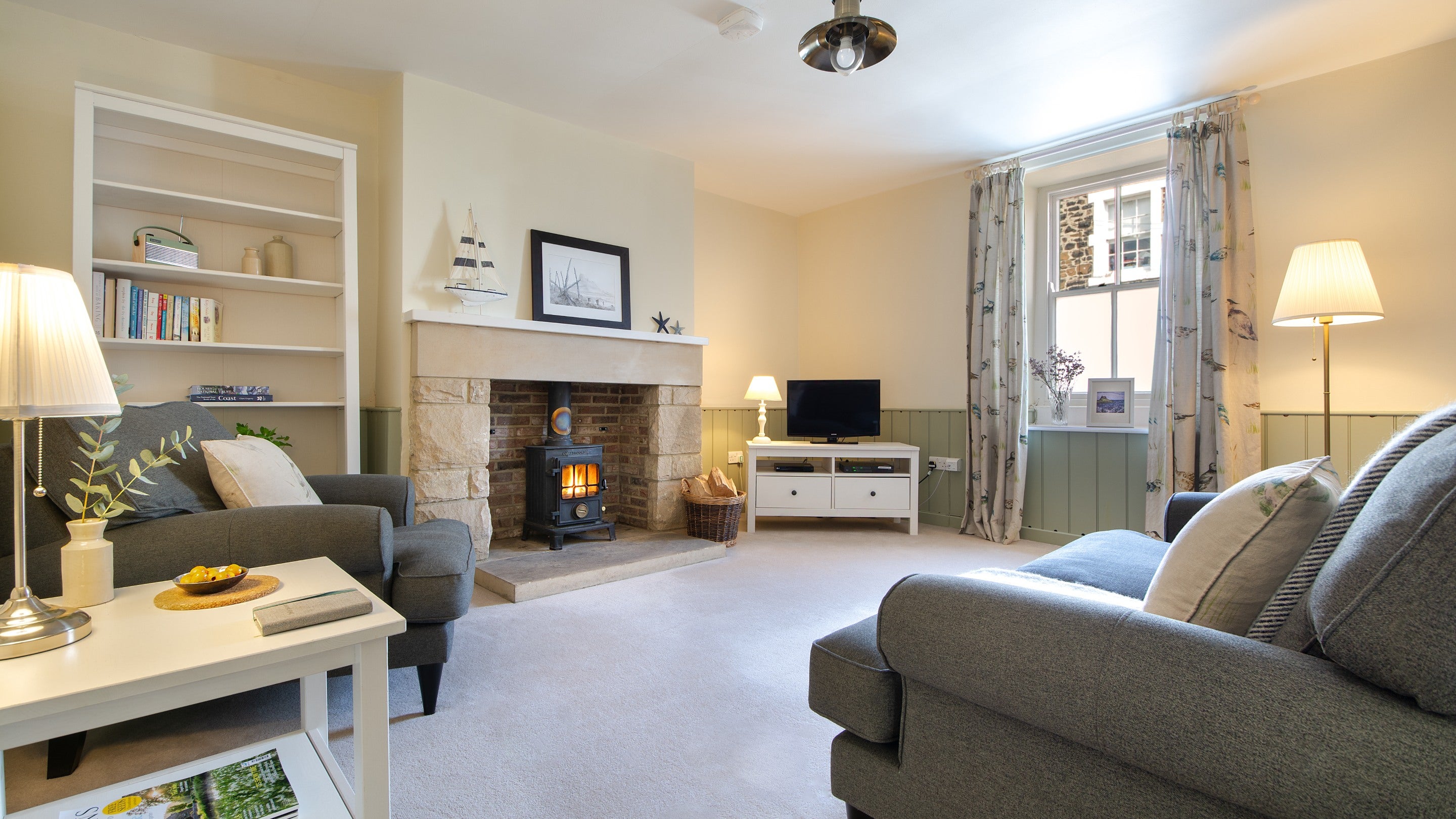 The sitting room with sofa, armchair, television and wood burning stove at Glen House, Northumberland