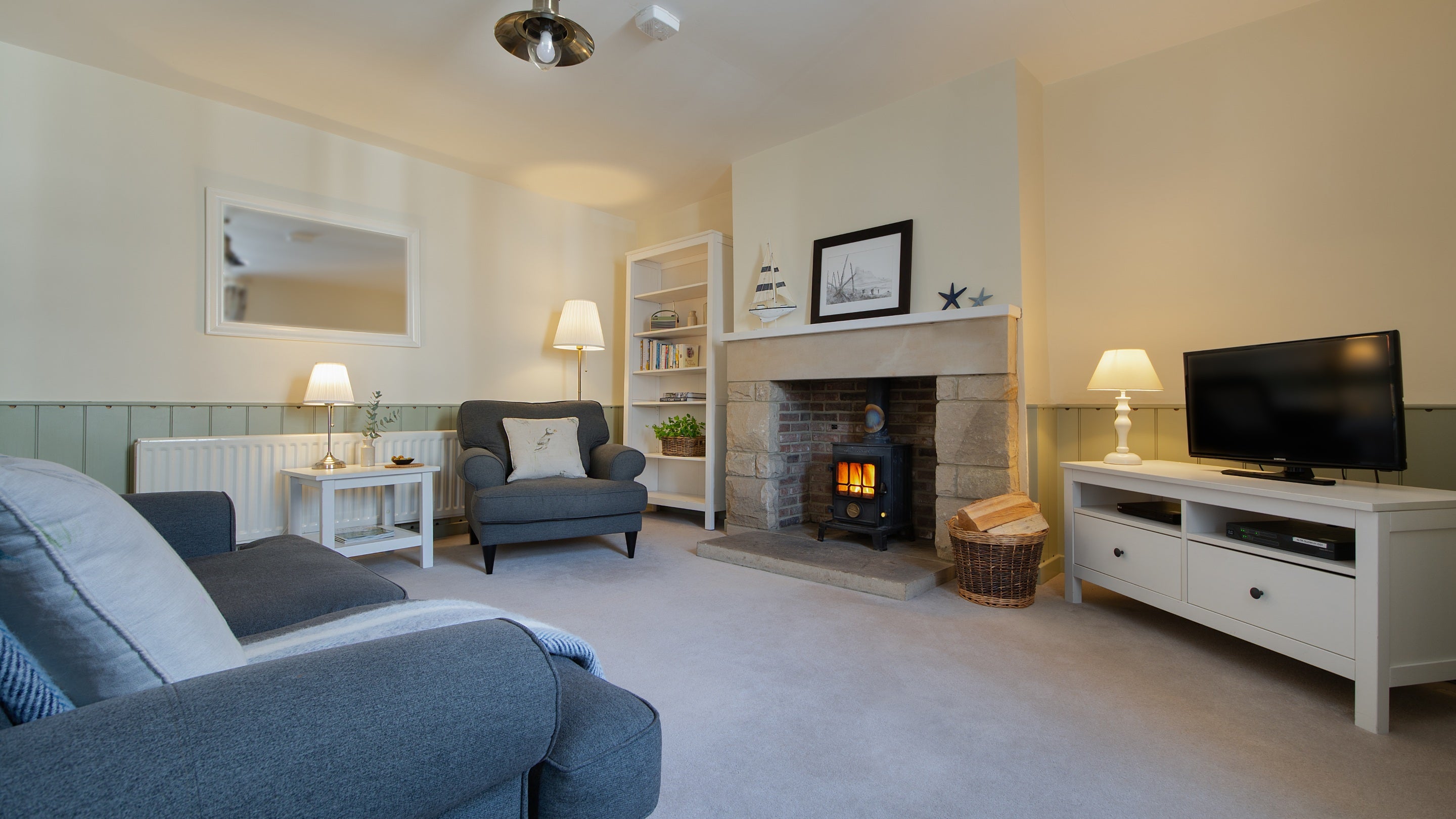 The sitting room with sofa, armchair, television and wood burning stove at Glen House, Northumberland