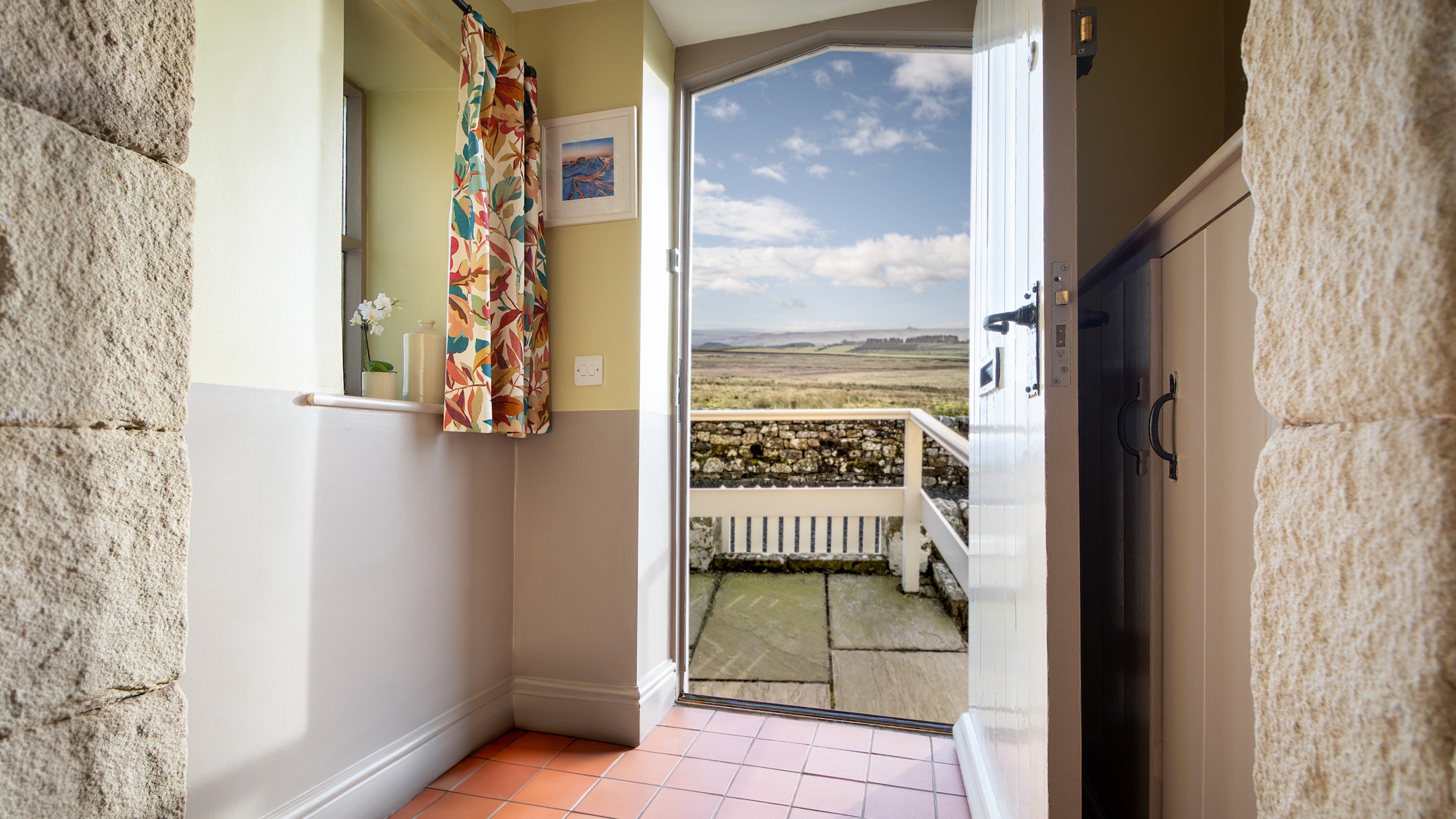 The entrance hall at Peel Cottage, with the door open, showing views of the surrounding countryside, Northumberland