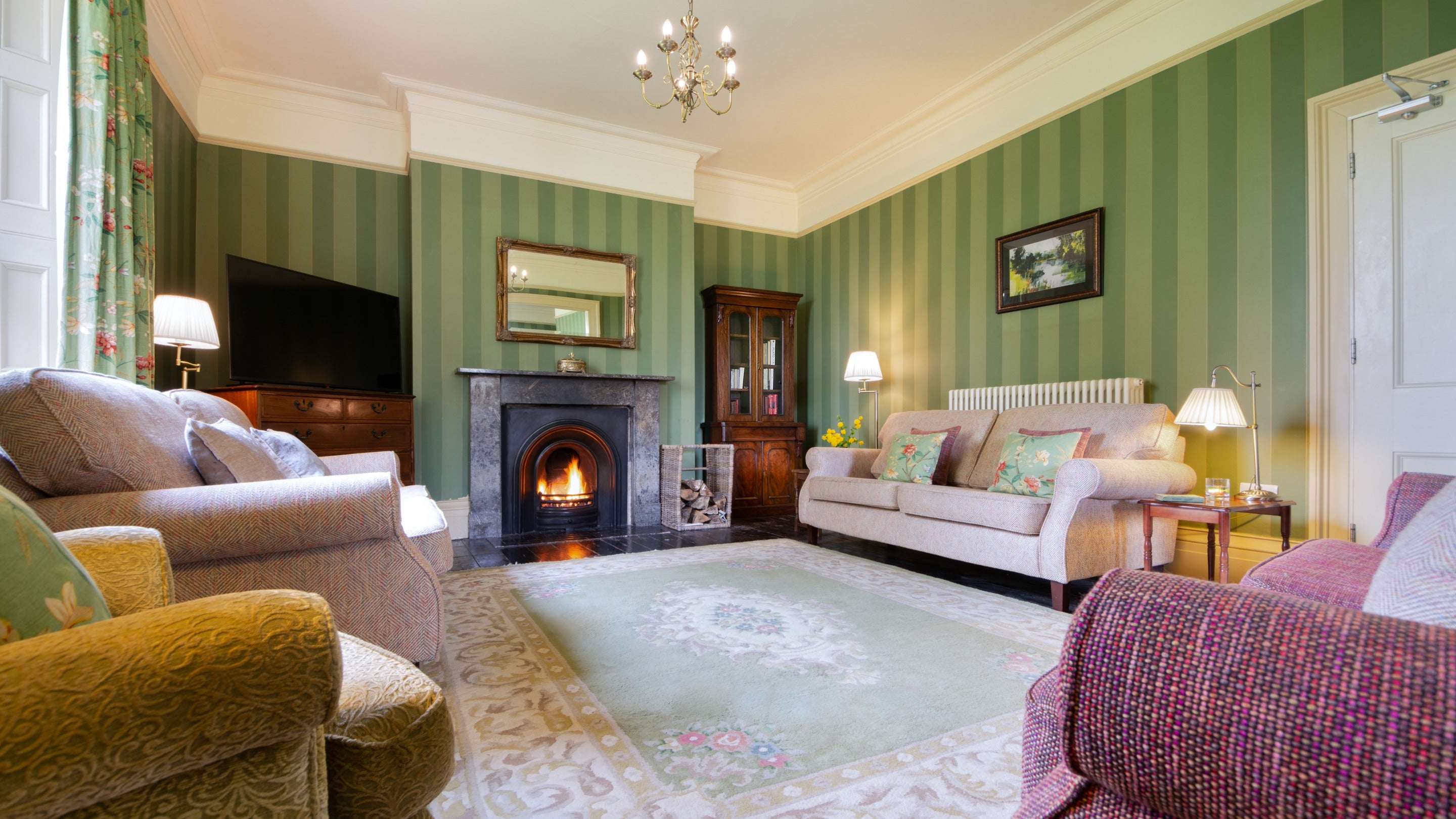The sitting room with open fire, sofas, armchair and television at Gunby Old Rectory, Lincolnshire