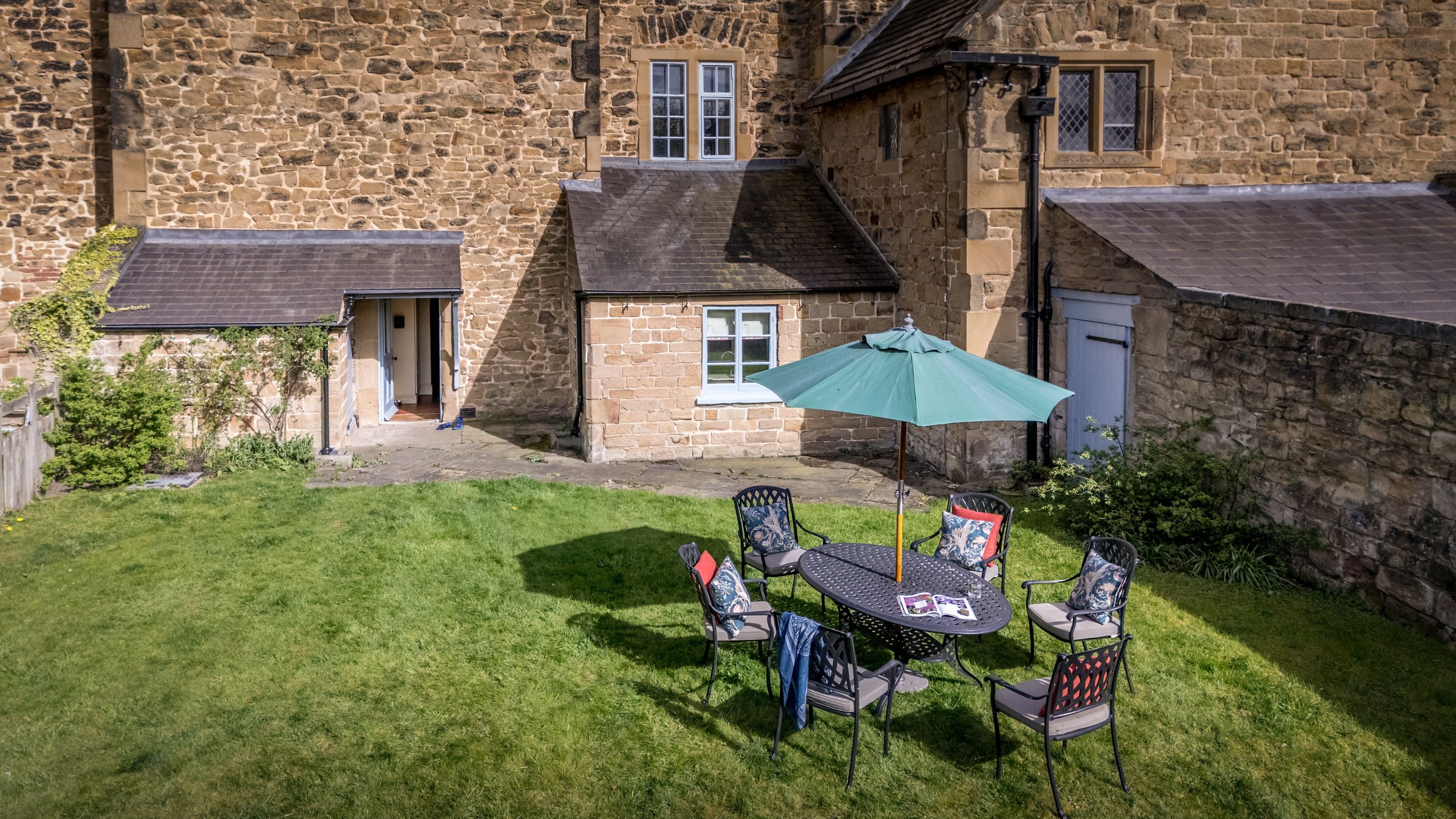 An aerial view of the garden at 4 Stable Yard Cottage, with lawn and an outdoor table and chairs, Derbyshire