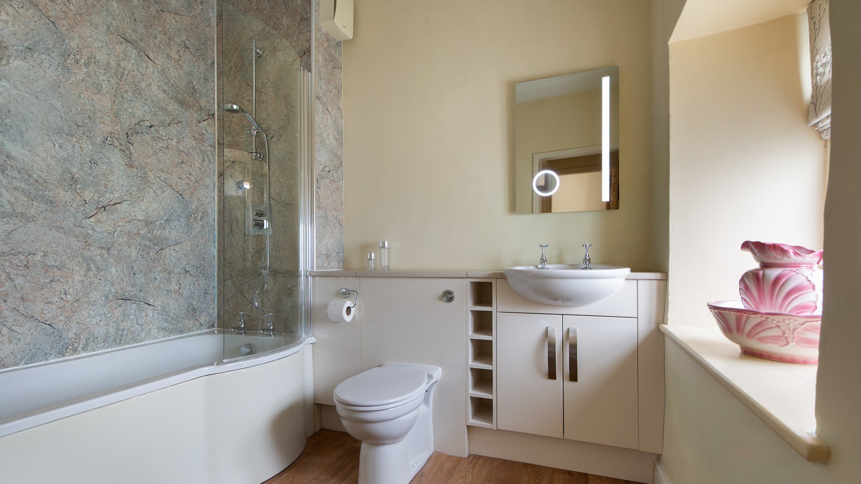 The en-suite bathroom with shower over bath, attached to the double bedroom with half tester bed at 4 Stable Yard Cottage, Derbyshire