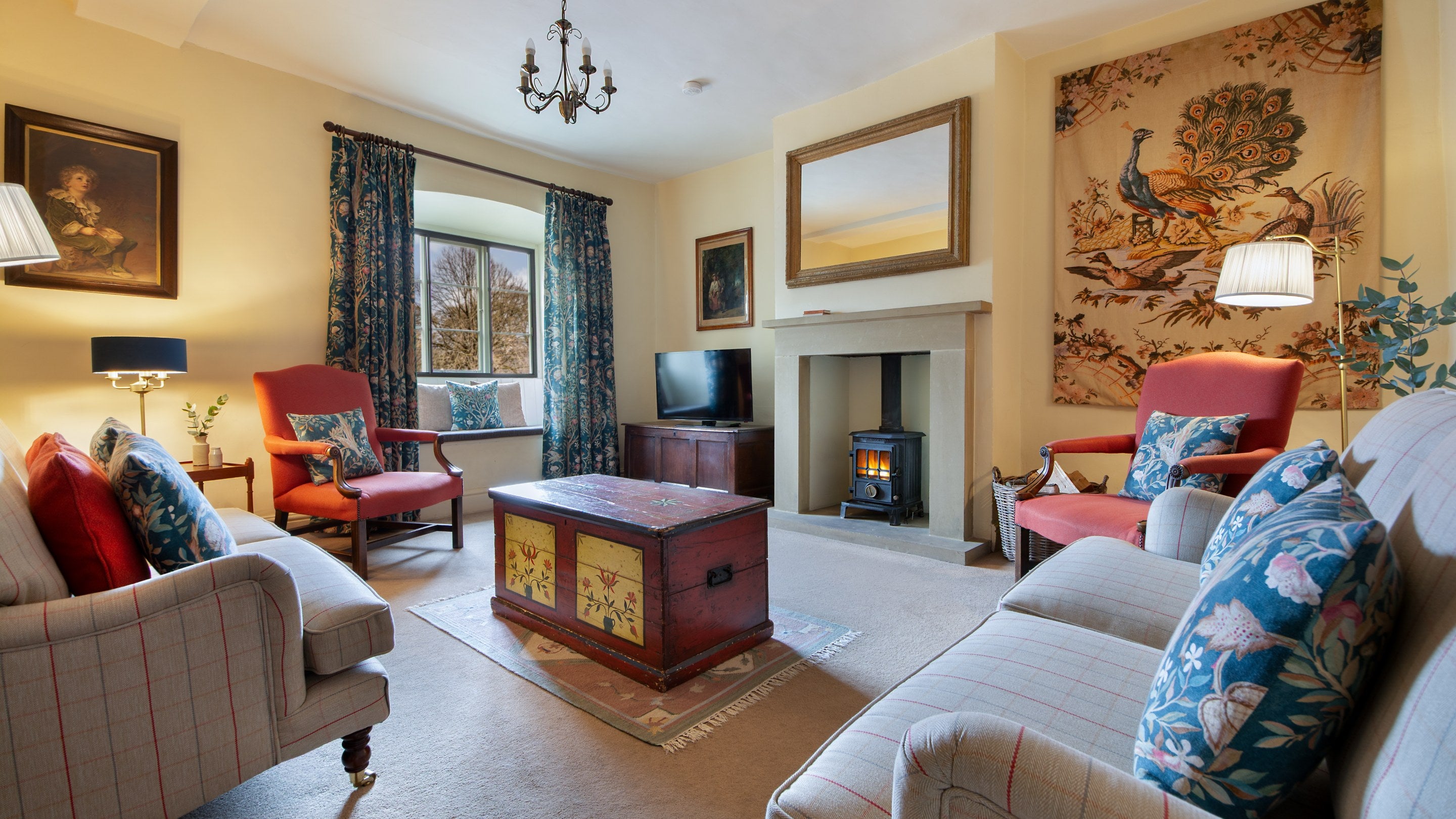 The sitting room at 4 Stable Yard Cottage, with two sofas, two armchairs, television and woodburner, Derbyshire