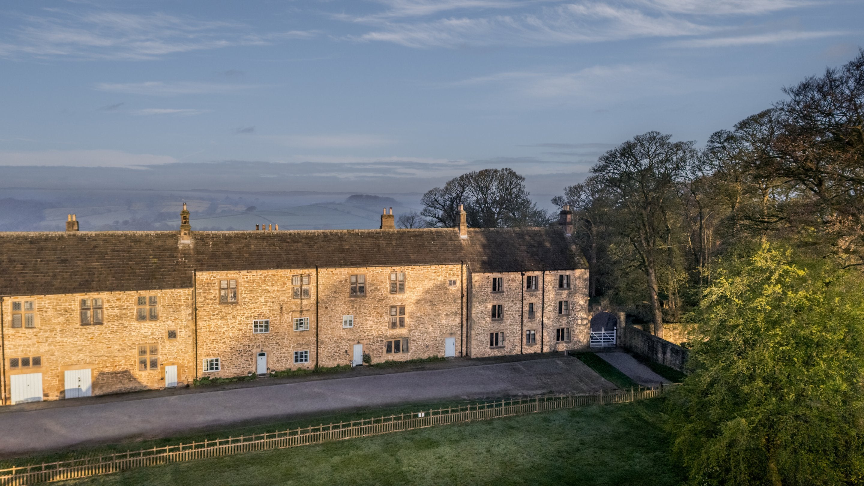 An aerial view of the holiday cottages, 6 High Hazels and 4 Stable Yard Cottage, and the attached buildings, with countryside in the distance beyond, Derbyshire