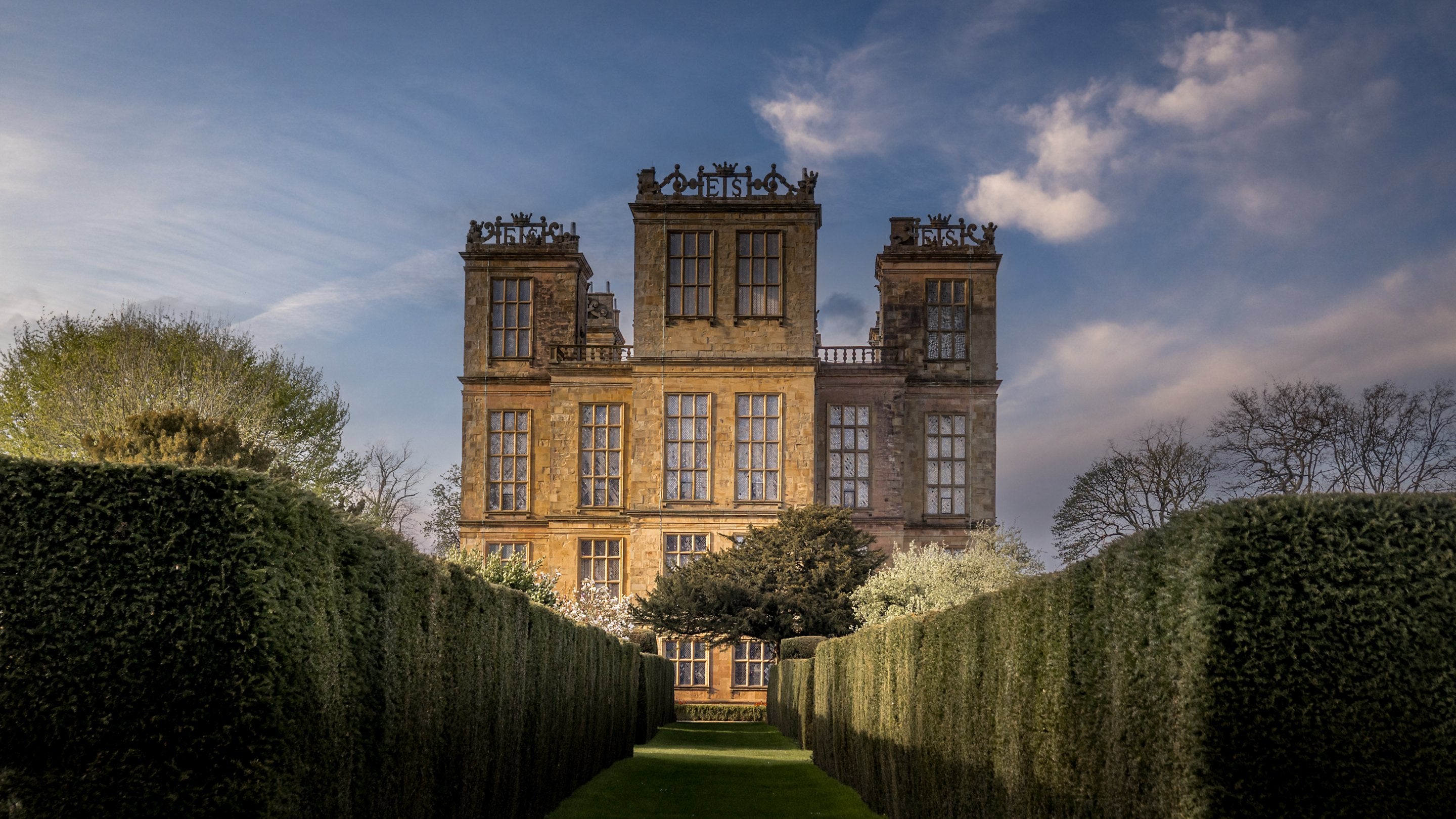 Looking down a path lined with tall hedges to Hardwick Hall, Derbyshire
