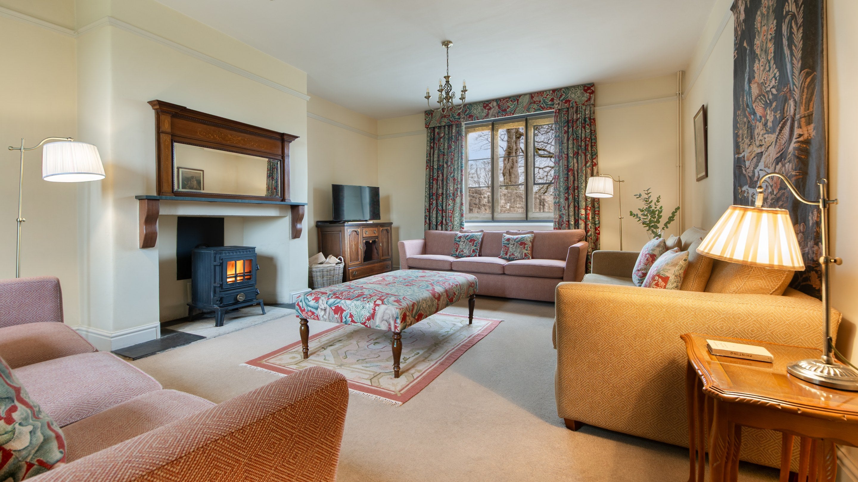 The sitting room at 6 High Hazels, with three sofas, television and a woodburner, Derbyshire