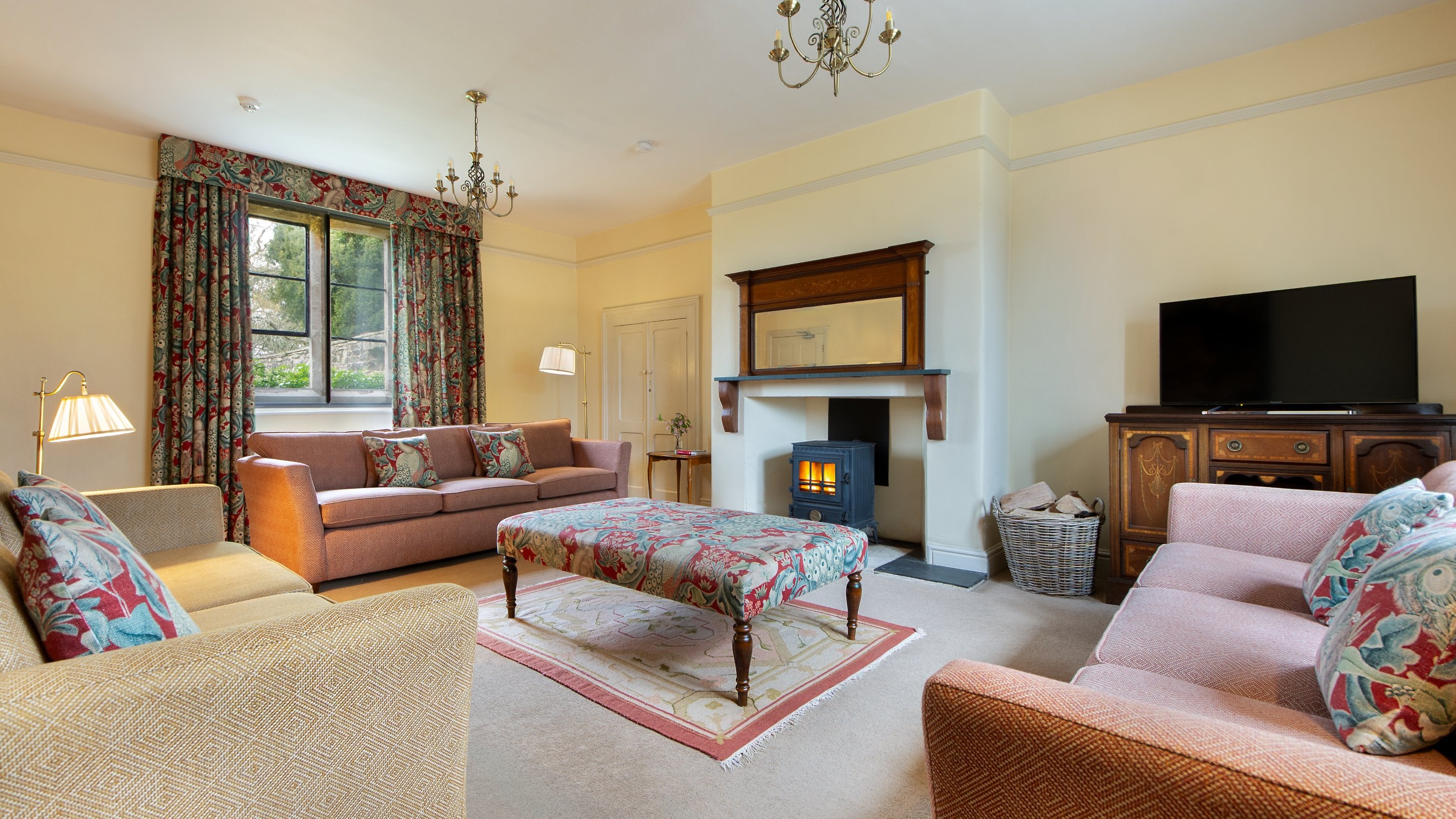 The sitting room at 6 High Hazels, with three sofas, television and a woodburner, Derbyshire