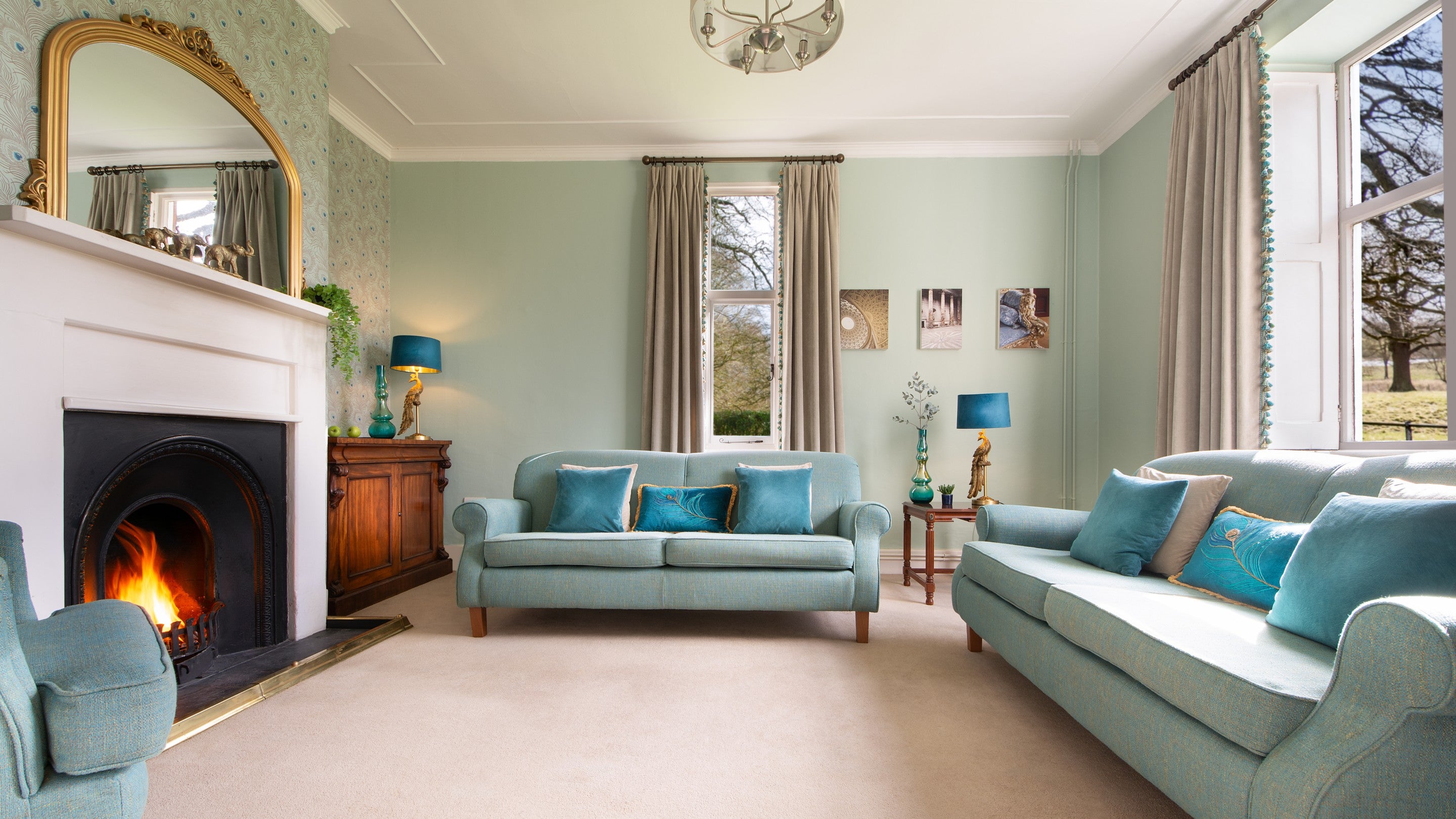 The sitting room with sofas, open fire and parkland views at Kedleston Park House, Derbyshire