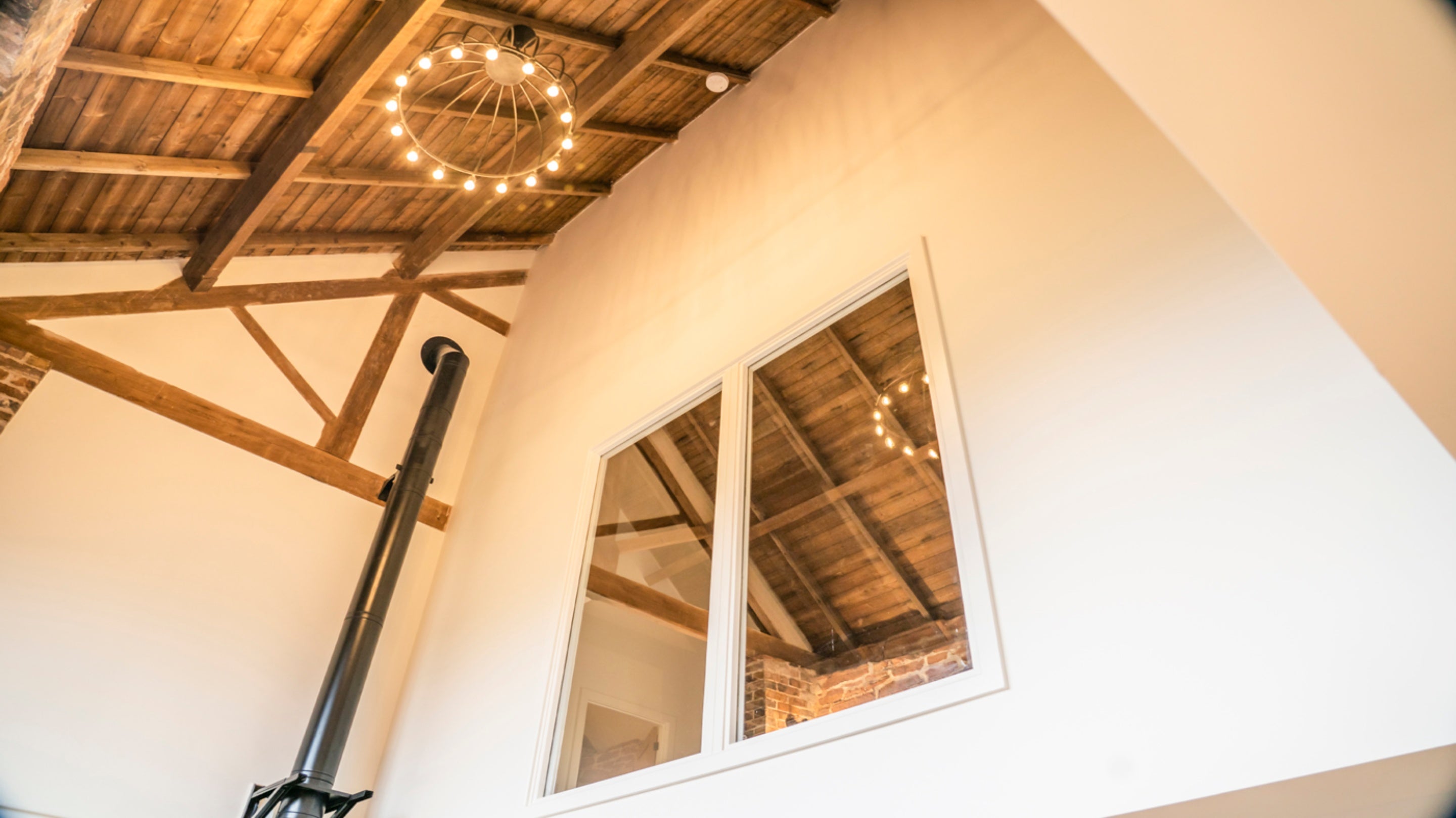 Looking up at the vaulted ceiling and mezzanine window from the open-plan living space at Sandybury Barn, Shropshire