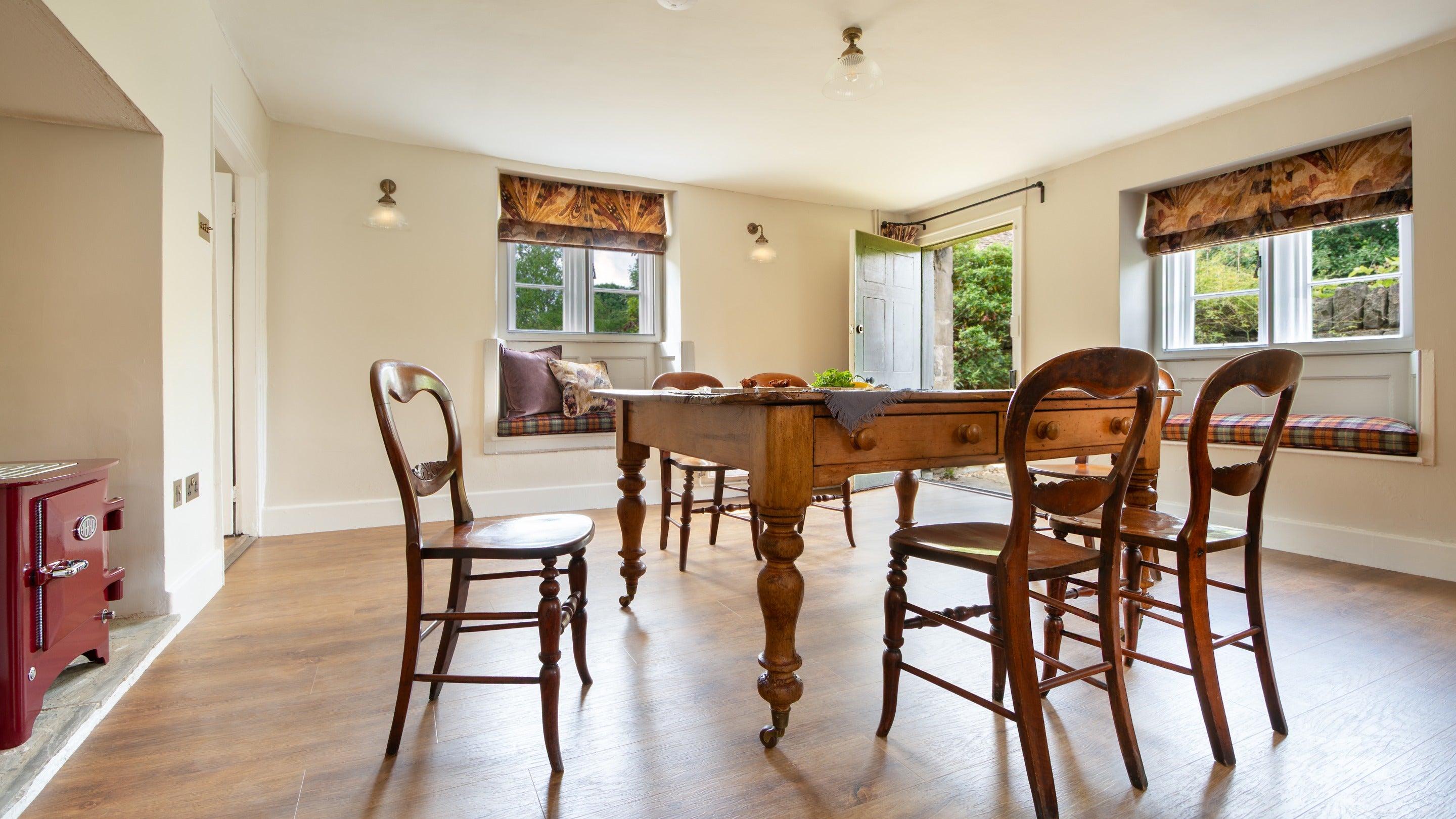 The open-plan kitchen and dining room, with Everhot stove, window seats and door to the back garden, at 20 Church Street, Wiltshire