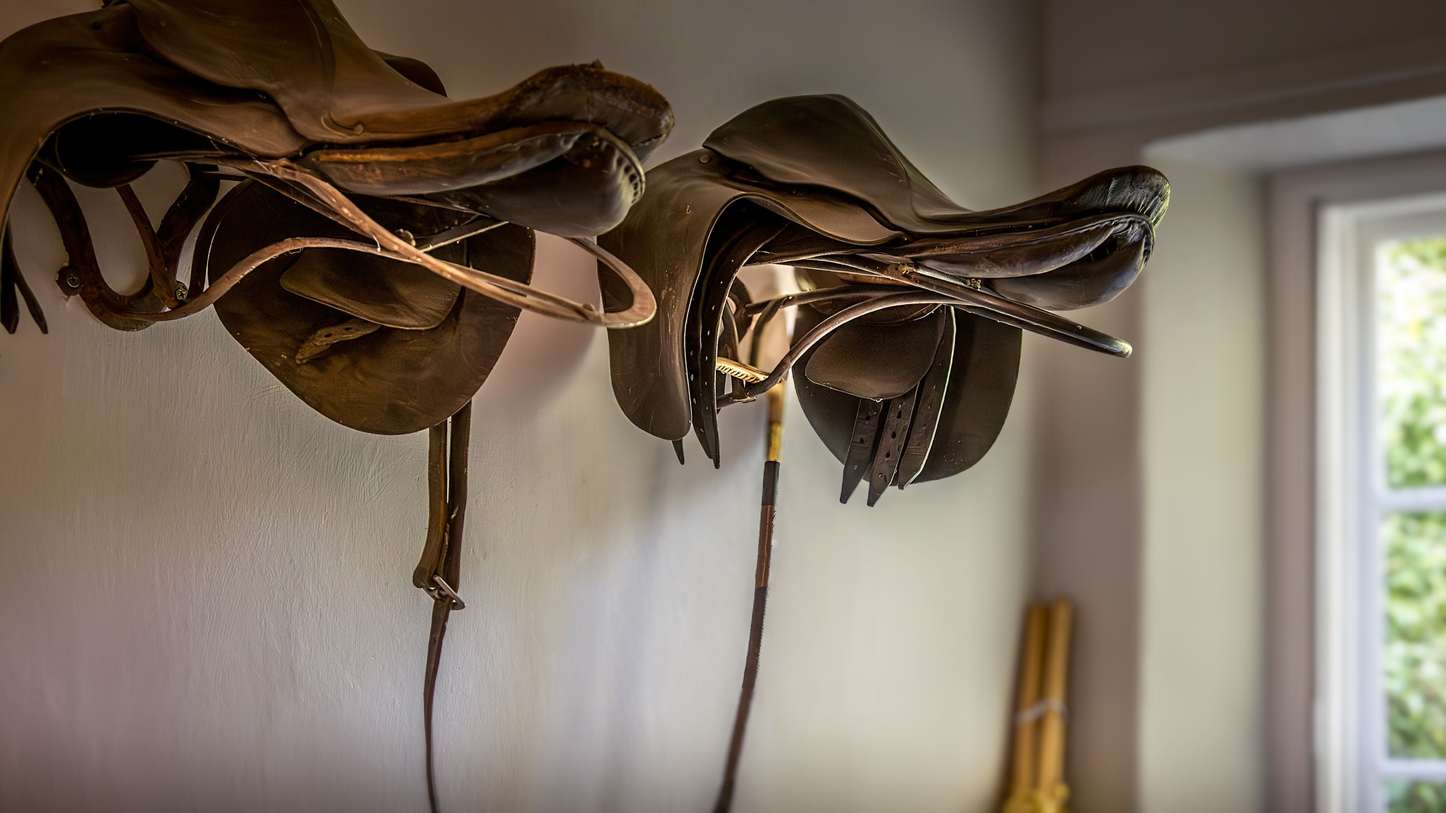Saddles displayed on the wall in the boot room at Selworthy Farmhouse, Somerset