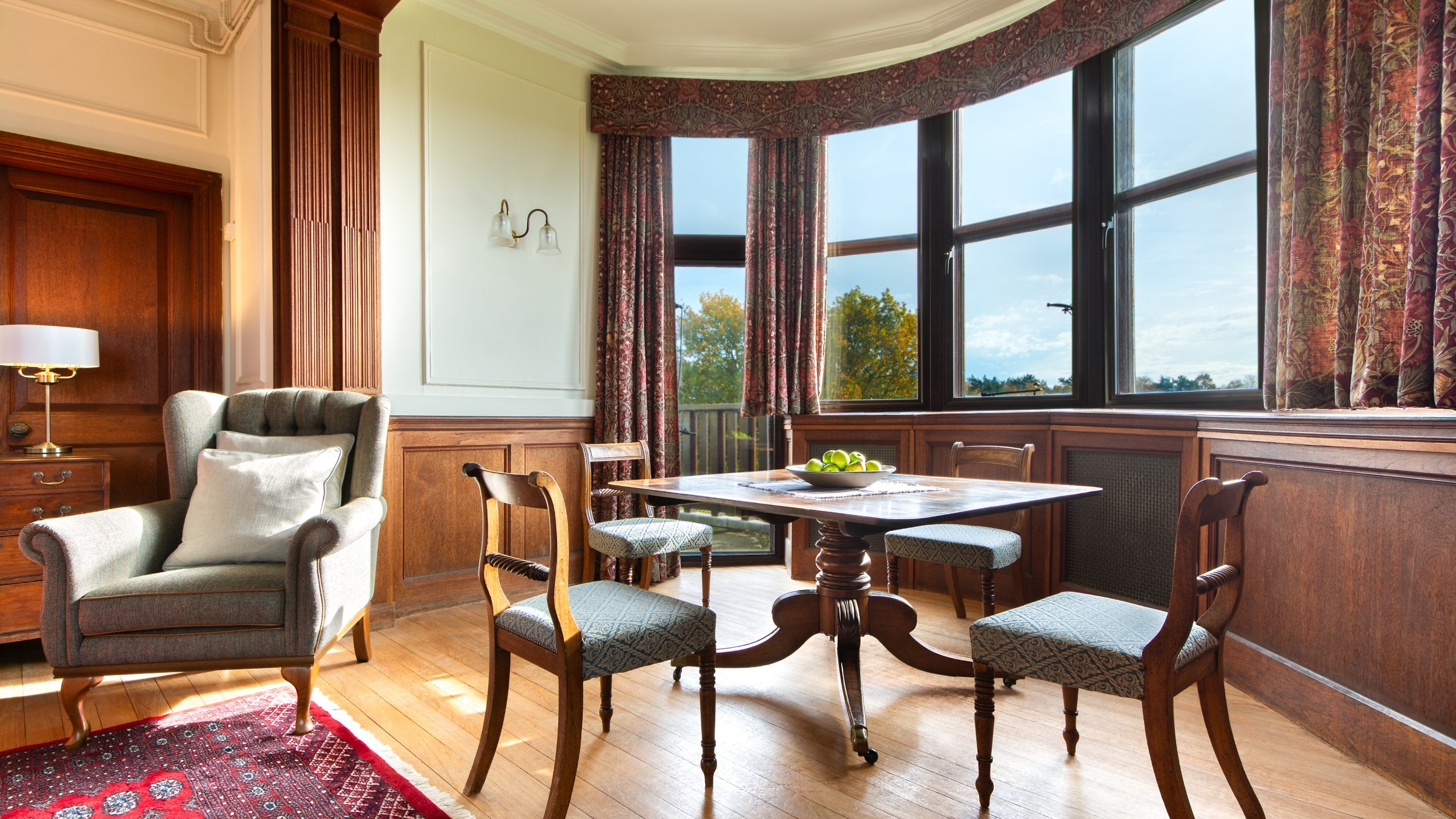 The dining area in the open-plan sitting and dining room at Deben View, with a large bay window overlooking Sutton Hoo, Suffolk