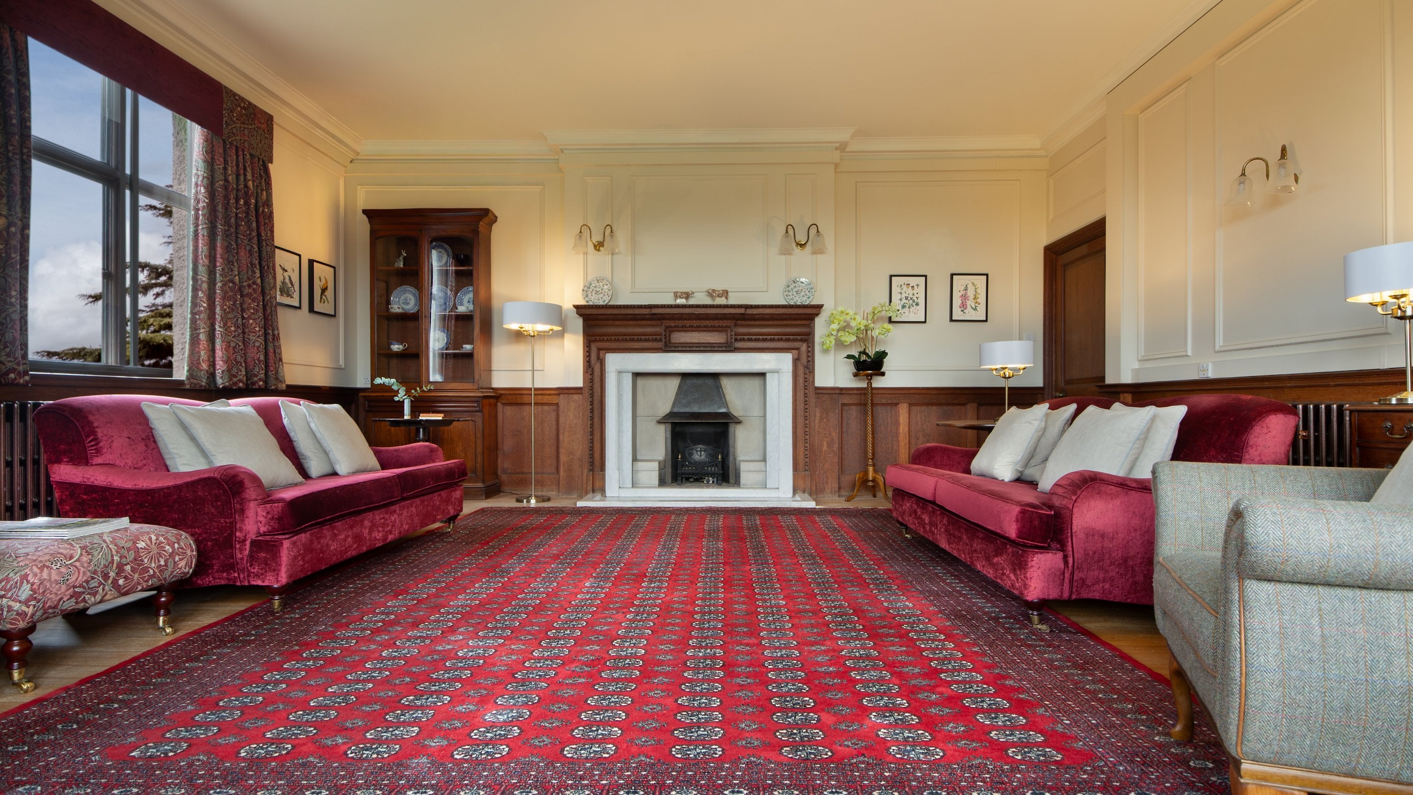 A view of the open-plan sitting and dining room at Deben View, showing two sofas, an armchair and an ornamental fireplace (not in use), Suffolk