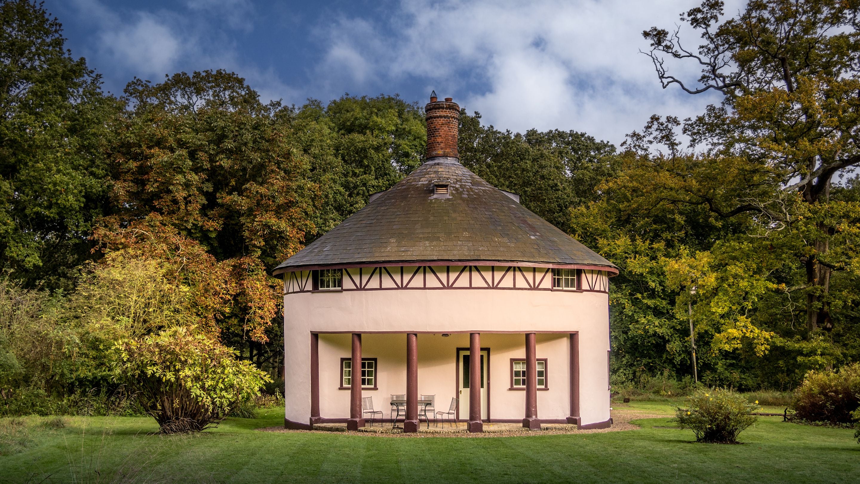 The exterior of The Round House, a rotunda cottage with a portico over a patio, Suffolk