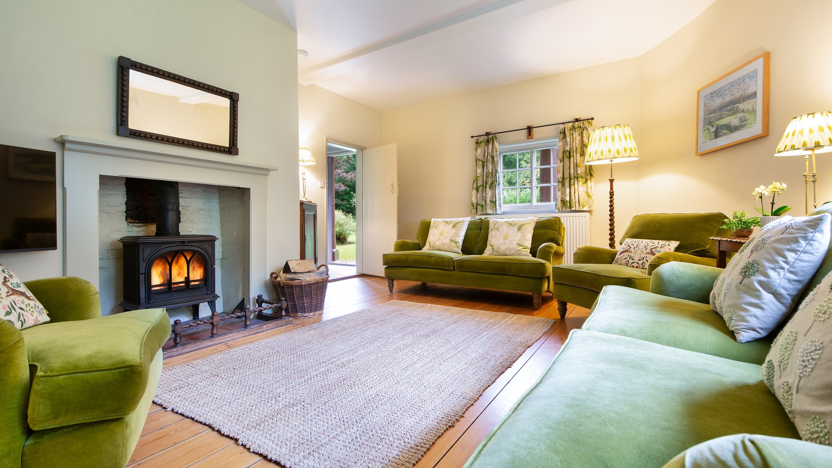 The sitting room at The Round House, with woodburner, television, sofas and armchairs, and a curved outer wall, Suffolk